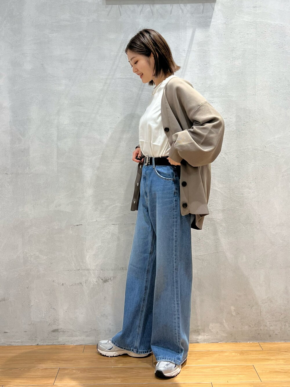 ブルー系のデニムパンツ、グレー系のスニーカー、ホワイト系のTシャツ/カットソーを着用したレディースの秋コーディネートの2枚目の写真