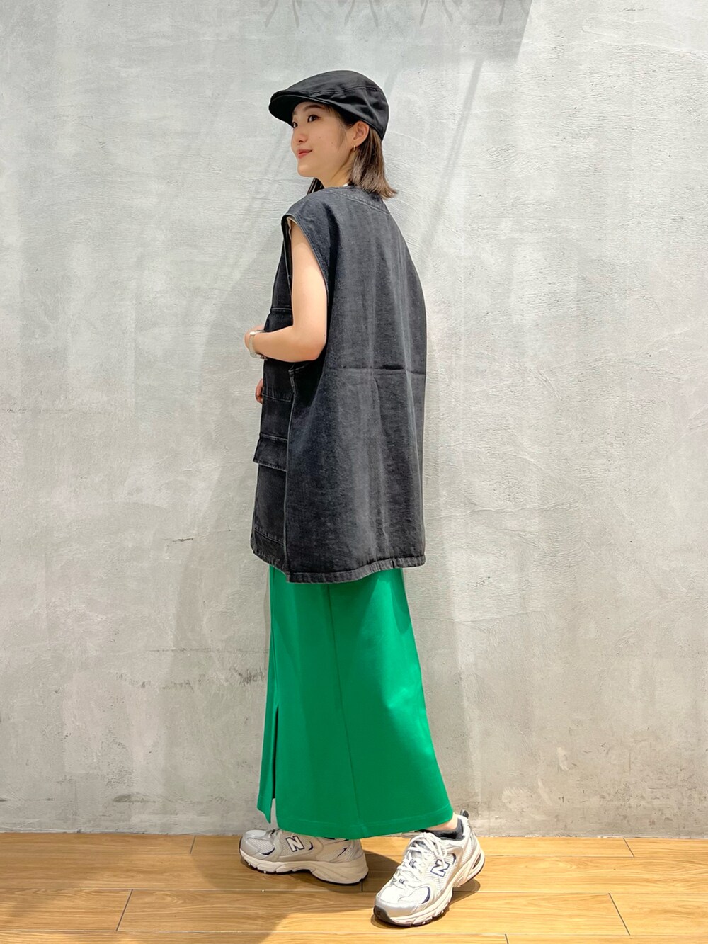 ブラック系のベスト、グリーン系のスカート、グレー系のスニーカーを着用したレディースの夏コーディネートの3枚目の写真