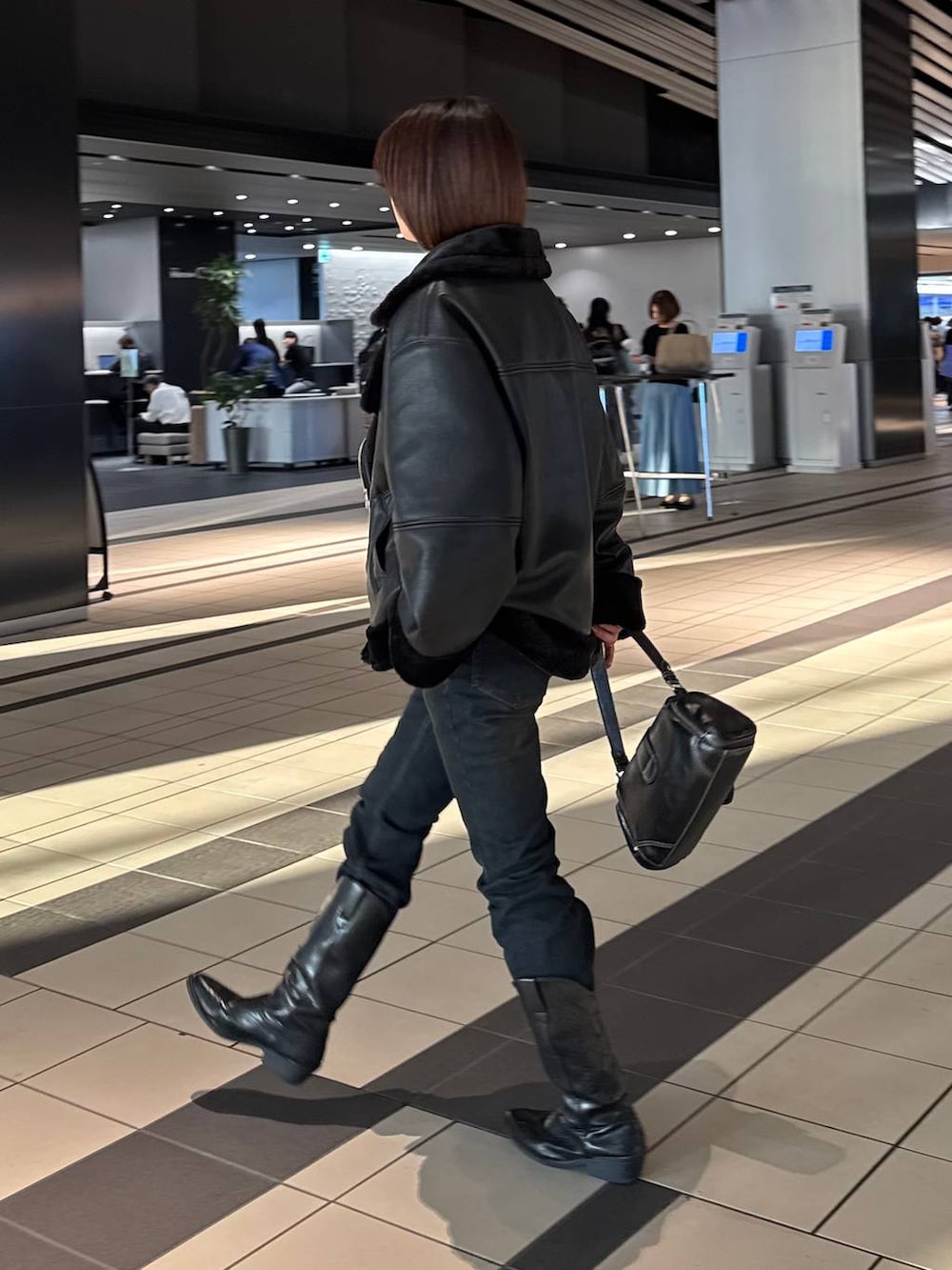ブラック系のデニムパンツ、ブラック系のライダースジャケット、ブラック系のショルダーバッグを着用したレディースの秋コーディネートの5枚目の写真
