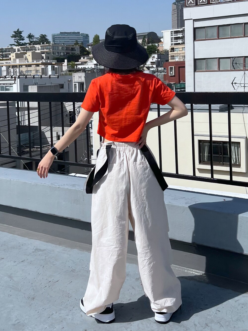 オレンジ系のTシャツ/カットソー、ホワイト系のその他パンツ、ブラック系のハットを着用したレディースの春コーディネートの3枚目の写真