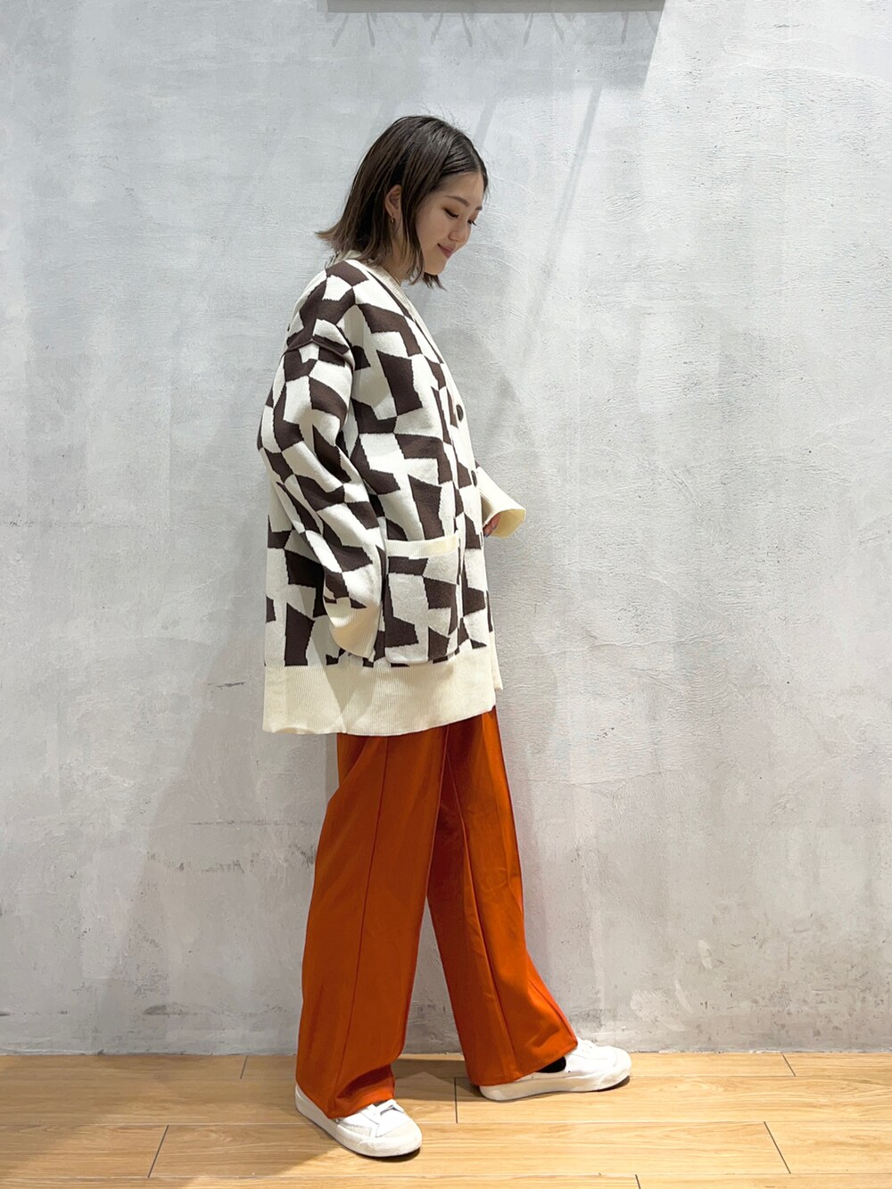 オレンジ系のスラックス、ブラウン系のカーディガン/ボレロを着用したレディースの秋コーディネートの2枚目の写真