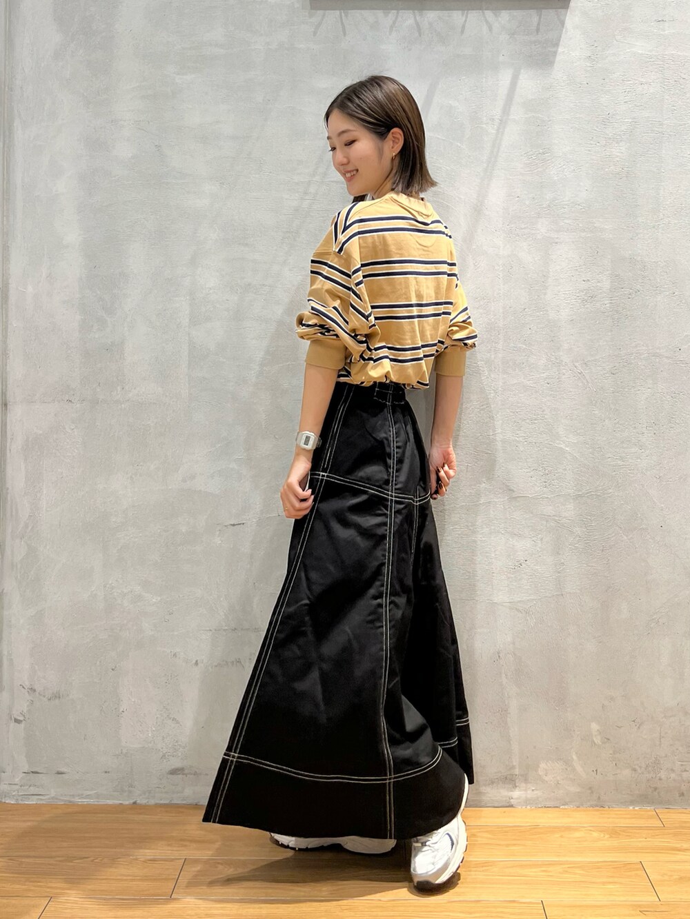 ブラック系のスカート、ベージュ系のTシャツ/カットソーを着用したレディースの秋コーディネートの2枚目の写真