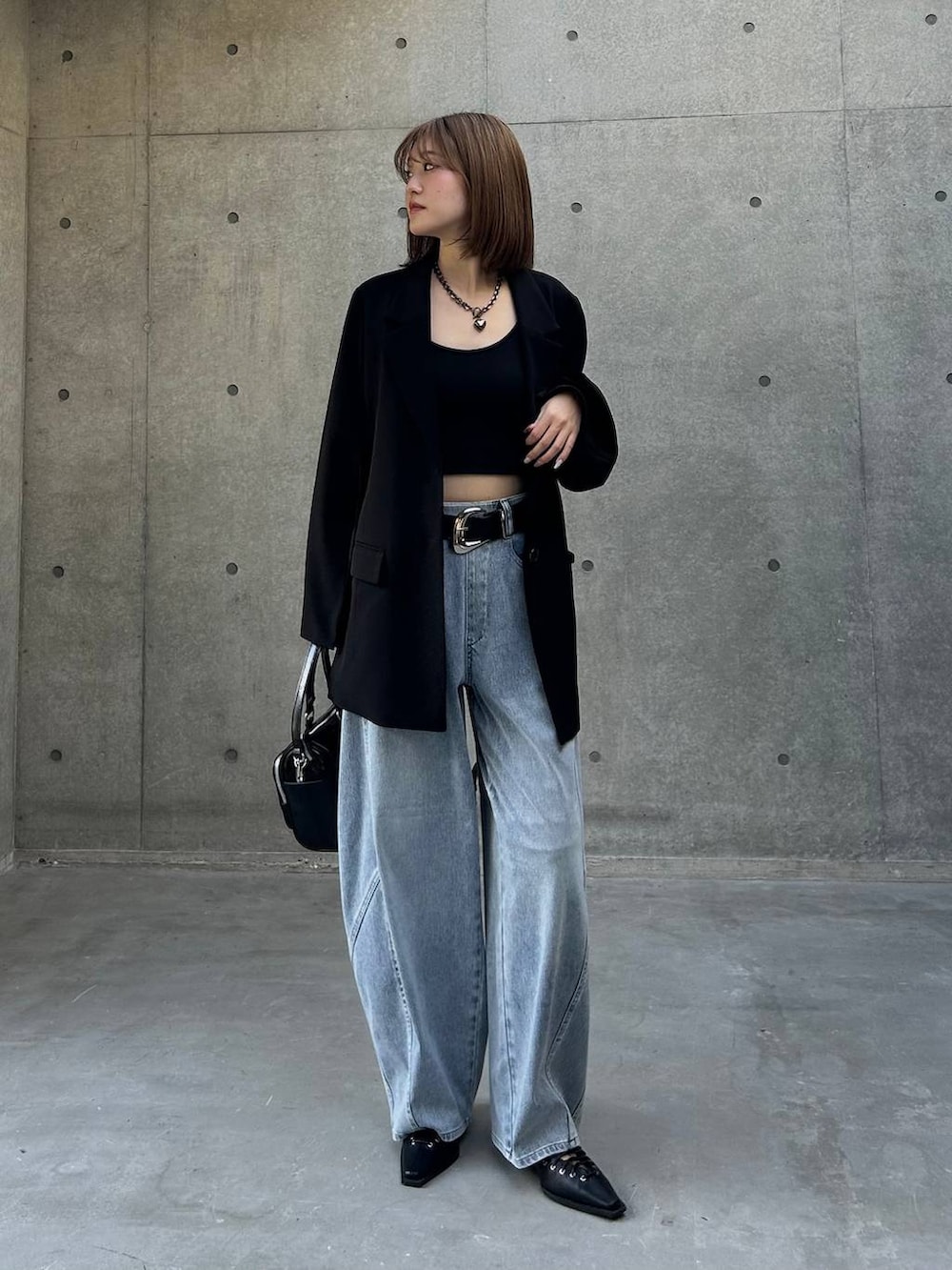ブラック系のテーラードジャケット、ブラック系のショルダーバッグ、ブルー系のデニムパンツを着用したレディースの春コーディネートの3枚目の写真