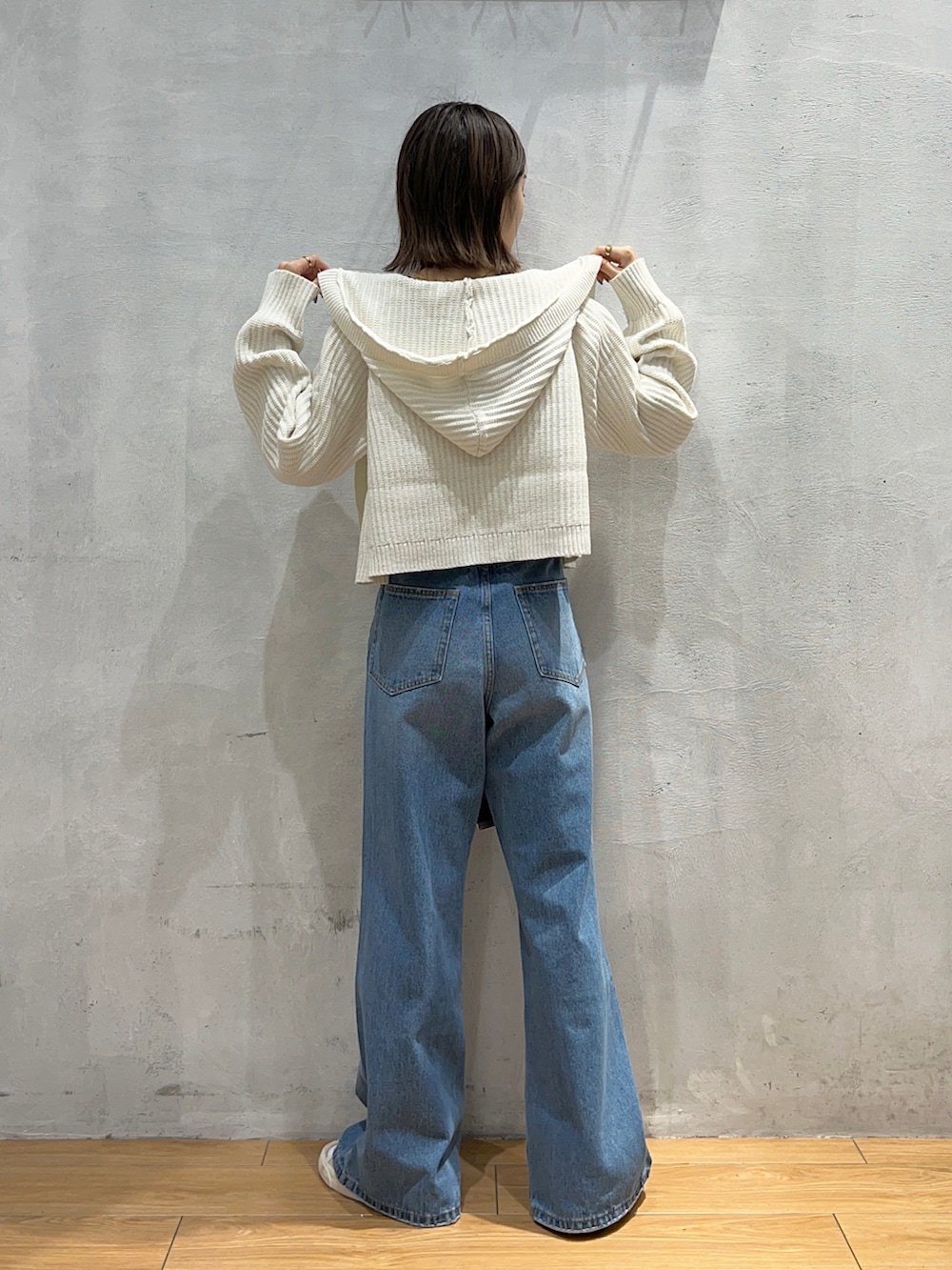 ブルー系のデニムパンツ、ホワイト系のカーディガン/ボレロ、ホワイト系のキャミソールを着用したレディースの秋コーディネートの3枚目の写真