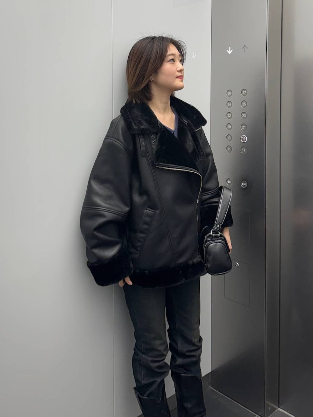 ブラック系のデニムパンツ、ブラック系のライダースジャケット、ブラック系のショルダーバッグを着用したレディースの秋コーディネートの4枚目の写真