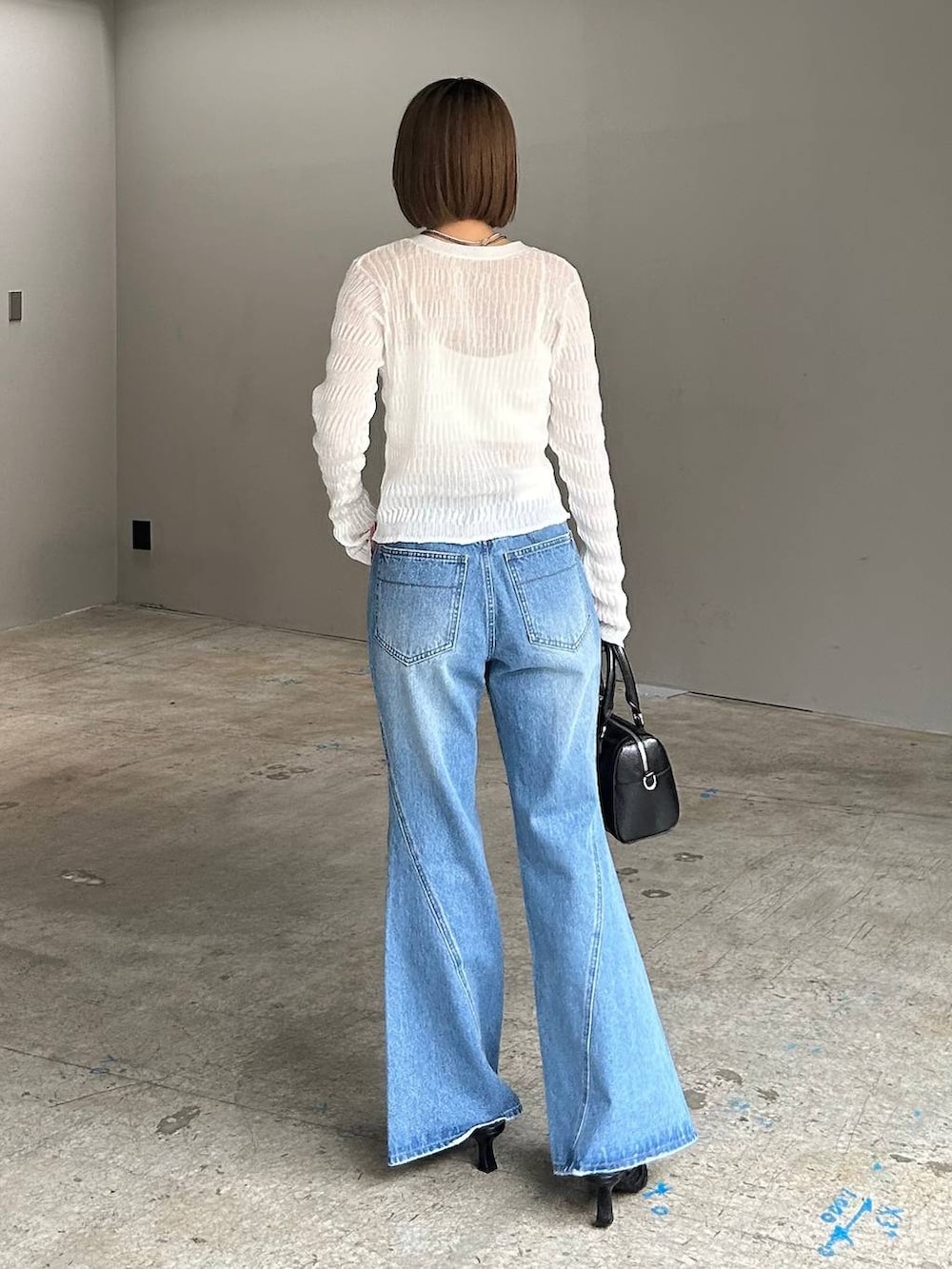 ホワイト系のキャミソール、ブルー系のデニムパンツ、ブラック系のボストンバッグを着用したレディースの春コーディネートの4枚目の写真