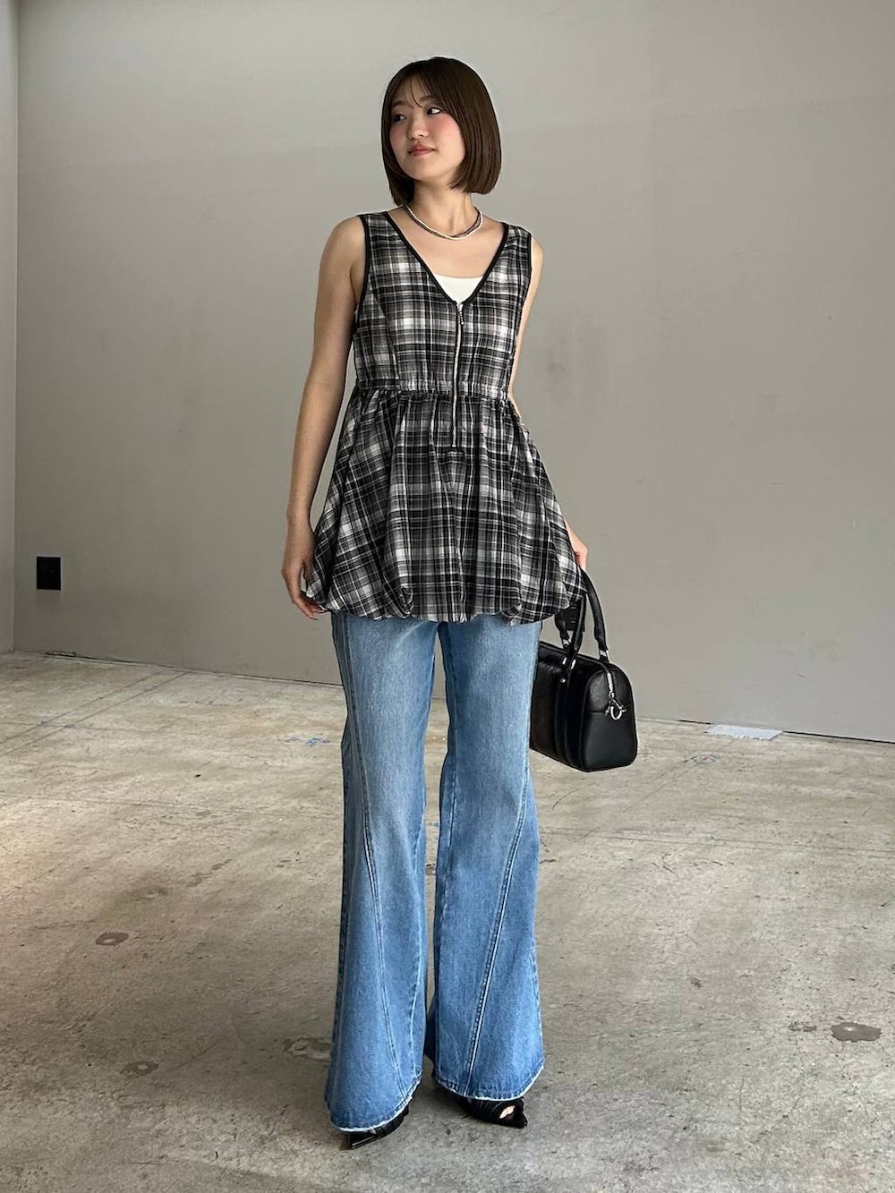 ブルー系のデニムパンツ、ブラック系のボストンバッグ、ブラック系のサンダルを着用したレディースの春コーディネートの5枚目の写真