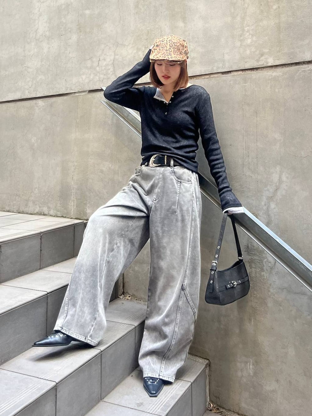 ブラック系のハンドバッグ、ブラック系のデニムパンツ、ブラック系のベルトを着用したレディースの冬コーディネートの2枚目の写真