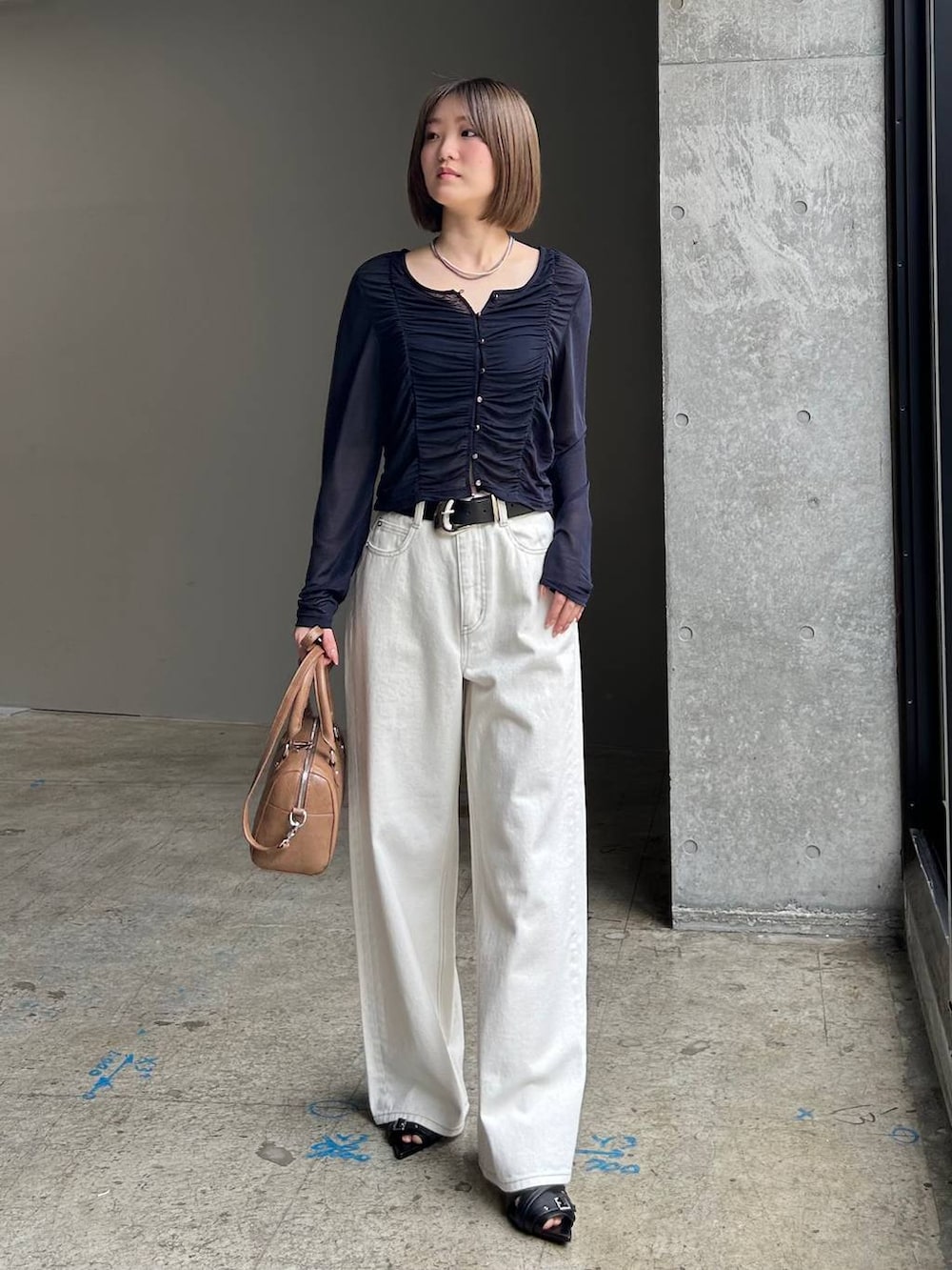 ホワイト系のスラックス、ブラウン系のボストンバッグ、ブラック系のベルトを着用したレディースの春コーディネートの3枚目の写真