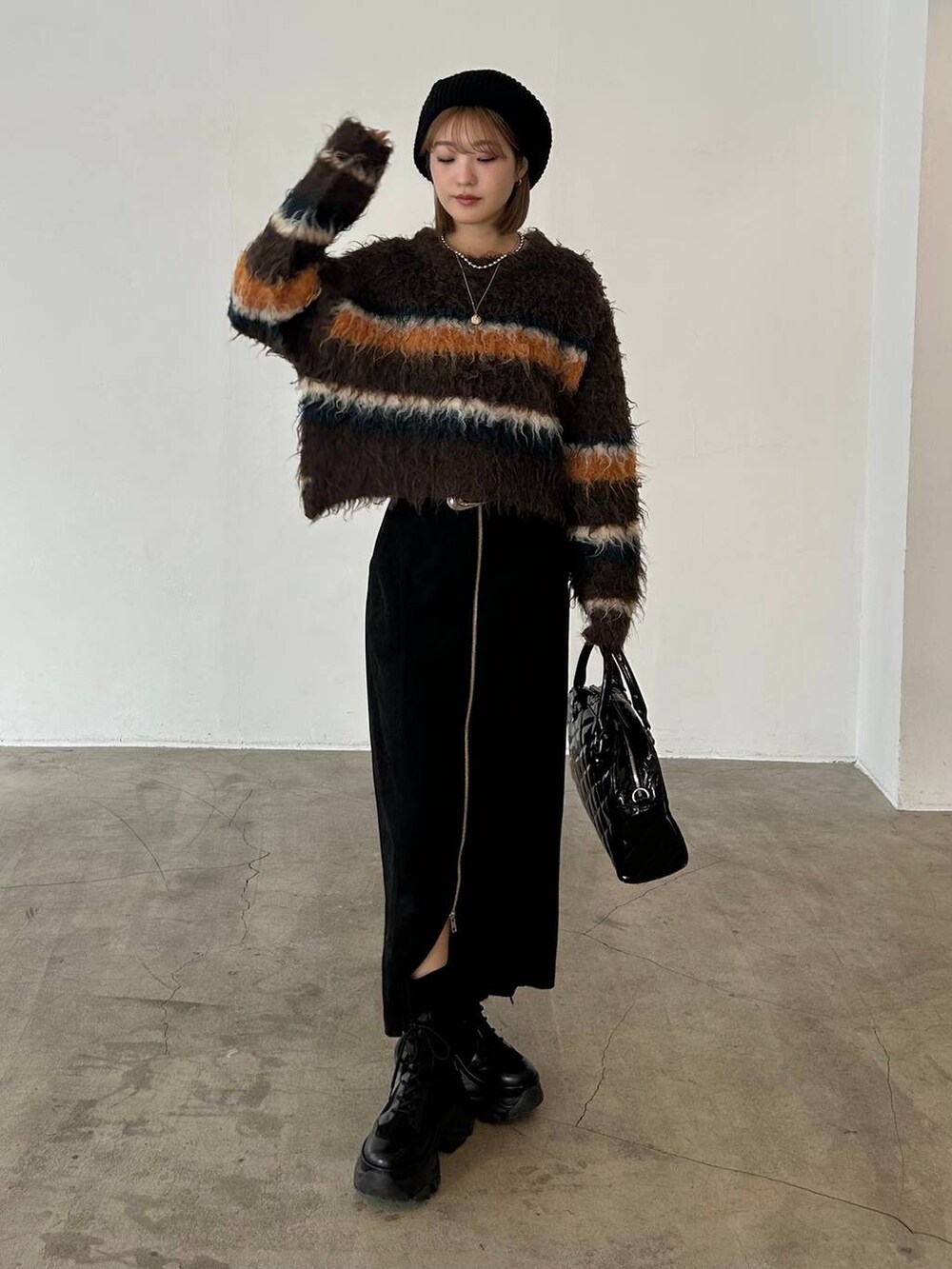 ブラック系のブーツ、ベージュ系のボストンバッグ、ブラウン系のニット/セーターを着用したレディースの冬コーディネートの4枚目の写真