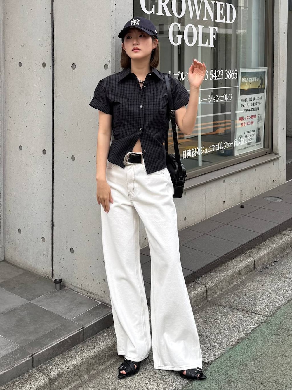 ホワイト系のデニムパンツ、ブラック系のショルダーバッグ、ブラック系のサンダルを着用したレディースの春コーディネートの3枚目の写真