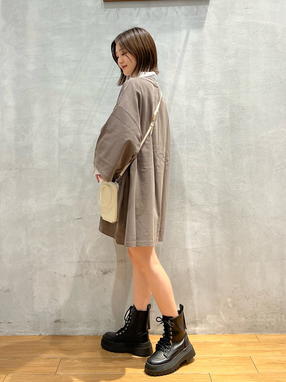 ブラウン系のTシャツ/カットソー、ブラック系のブーツ、ホワイト系のショルダーバッグを着用したレディースの秋コーディネートの2枚目の写真