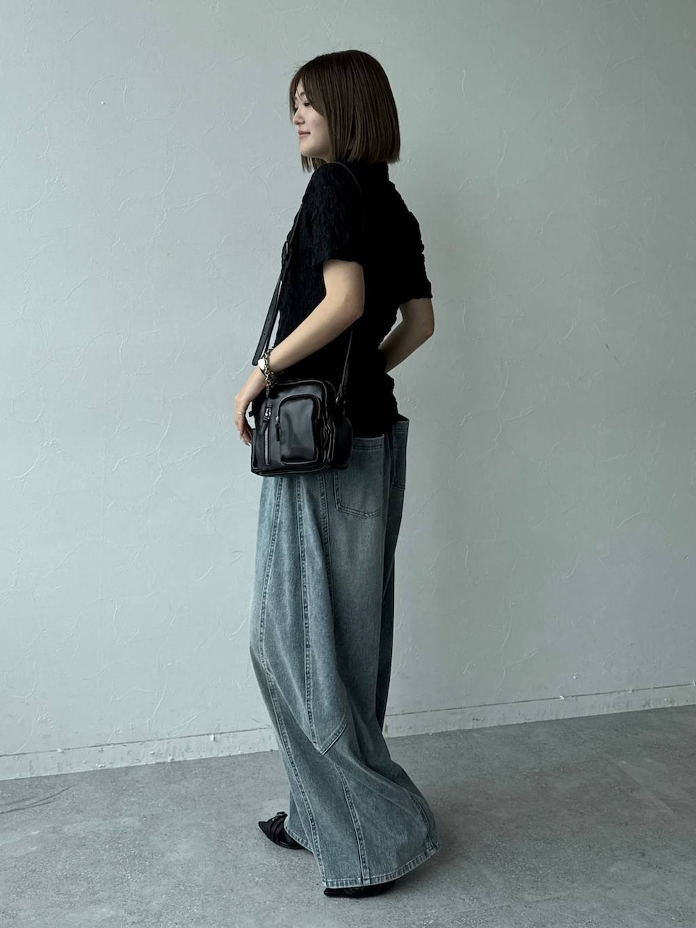 ブルー系のデニムパンツ、ブラック系のショルダーバッグ、ブラック系のサンダルを着用したレディースの春コーディネートの5枚目の写真
