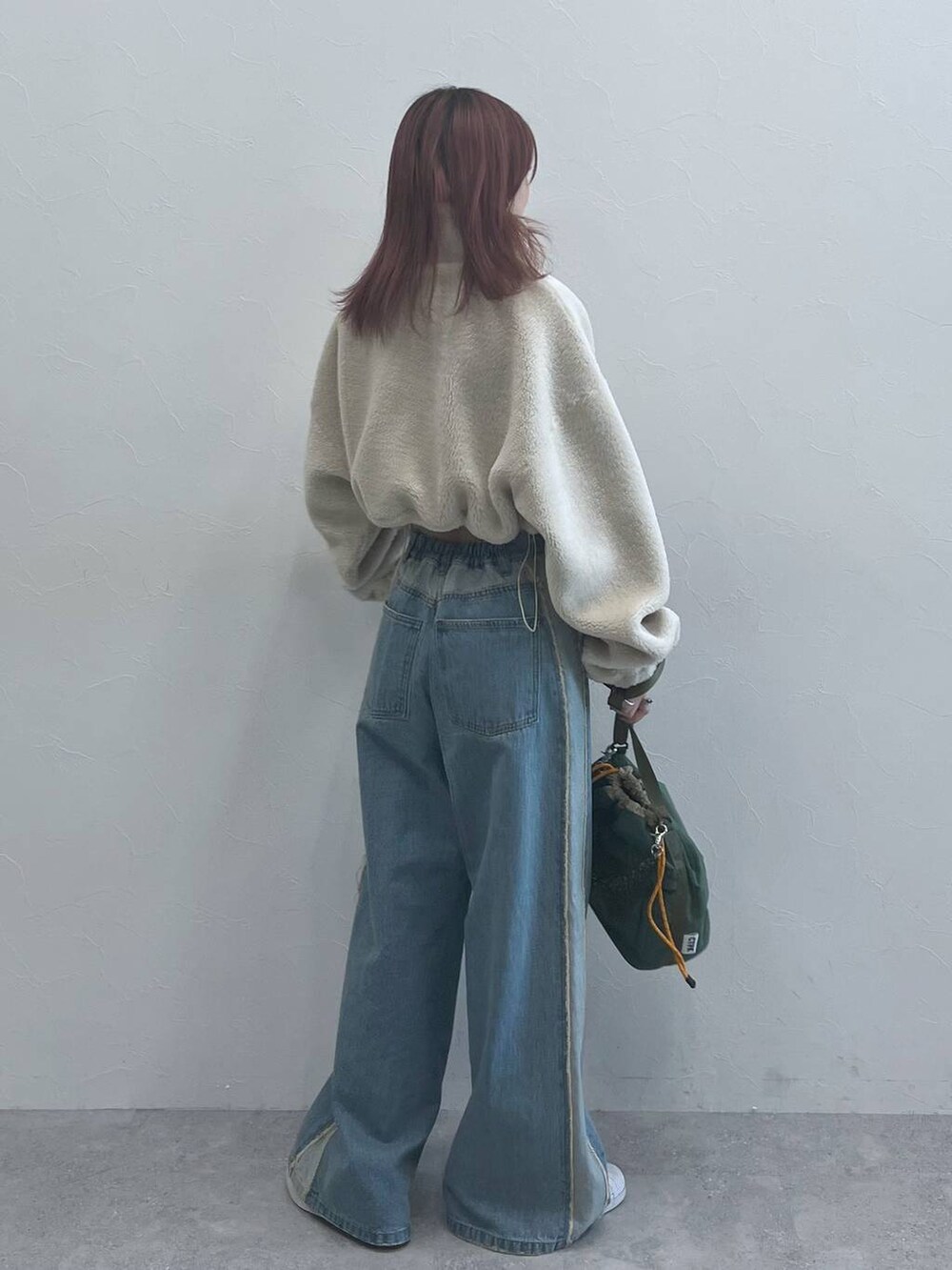 ブルー系のデニムパンツ、グリーン系のショルダーバッグを着用したレディースの秋コーディネートの3枚目の写真