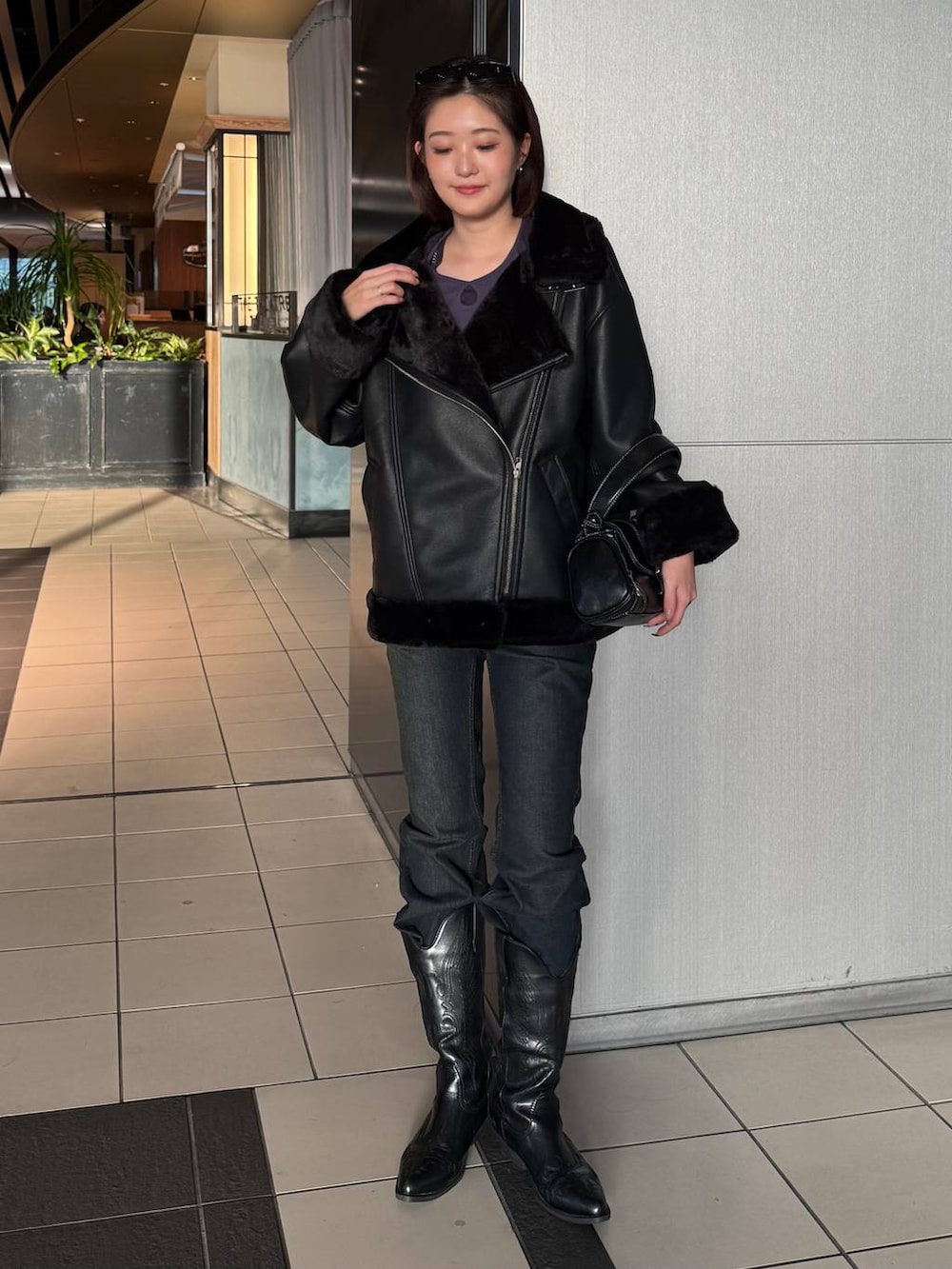 ブラック系のデニムパンツ、ブラック系のライダースジャケット、ブラック系のショルダーバッグを着用したレディースの秋コーディネートの2枚目の写真