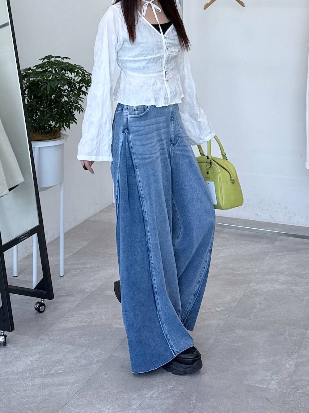 ブラック系のスニーカー、ブルー系のデニムパンツ、ホワイト系のシャツ/ブラウスを着用したレディースの春コーディネートの4枚目の写真