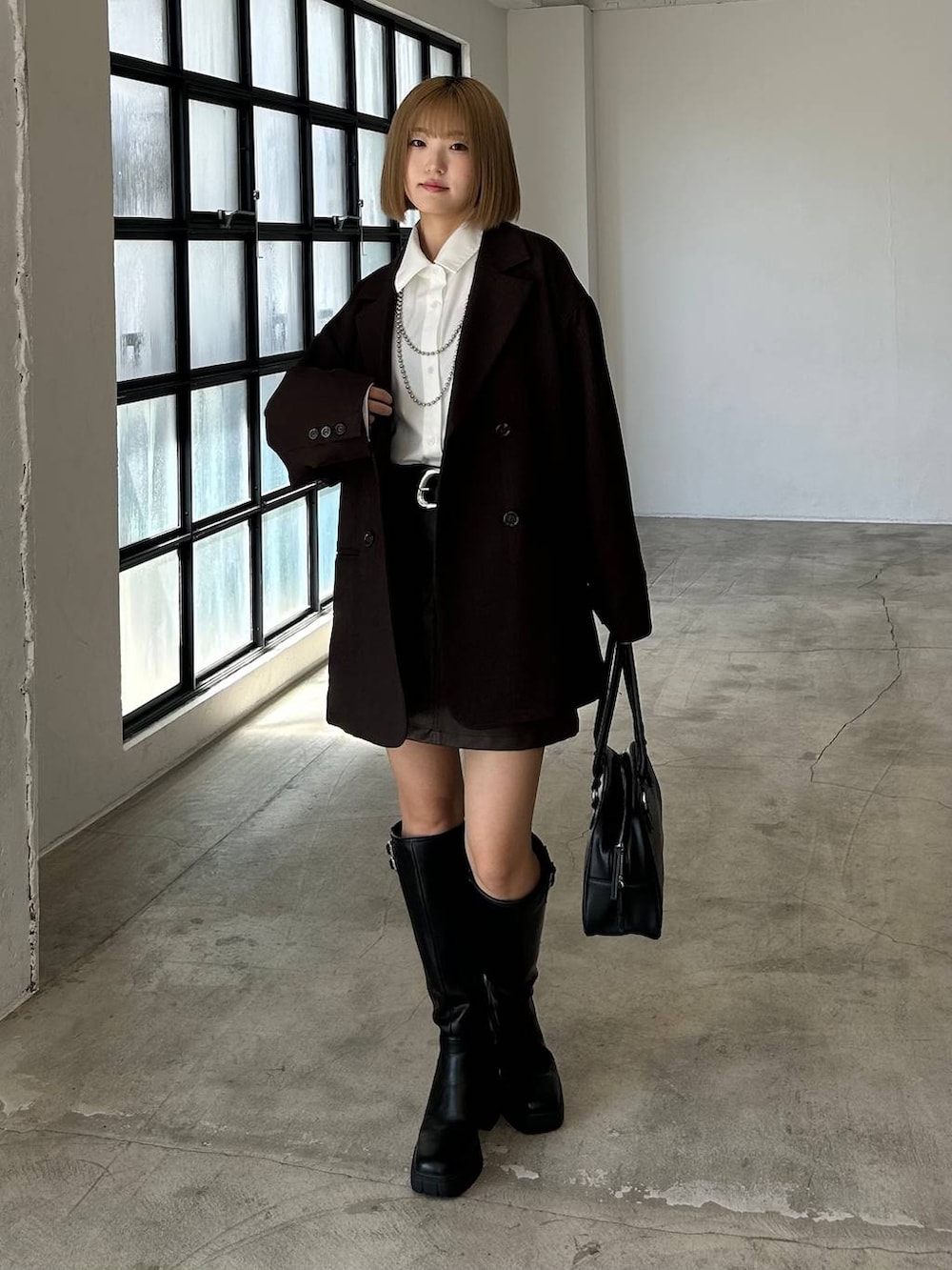 ブラック系のブーツ、ブラック系のボストンバッグ、ホワイト系のシャツ/ブラウスを着用したレディースの秋コーディネートの2枚目の写真