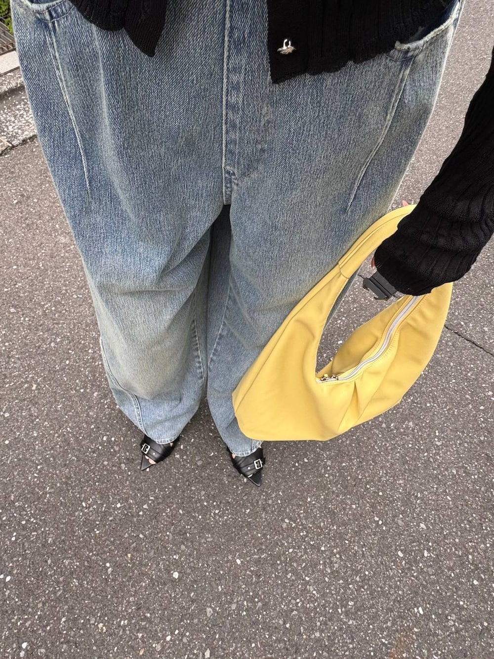 イエロー系のトートバッグ、ブルー系のデニムパンツ、ブラック系のカーディガン/ボレロを着用したレディースの春コーディネートの4枚目の写真