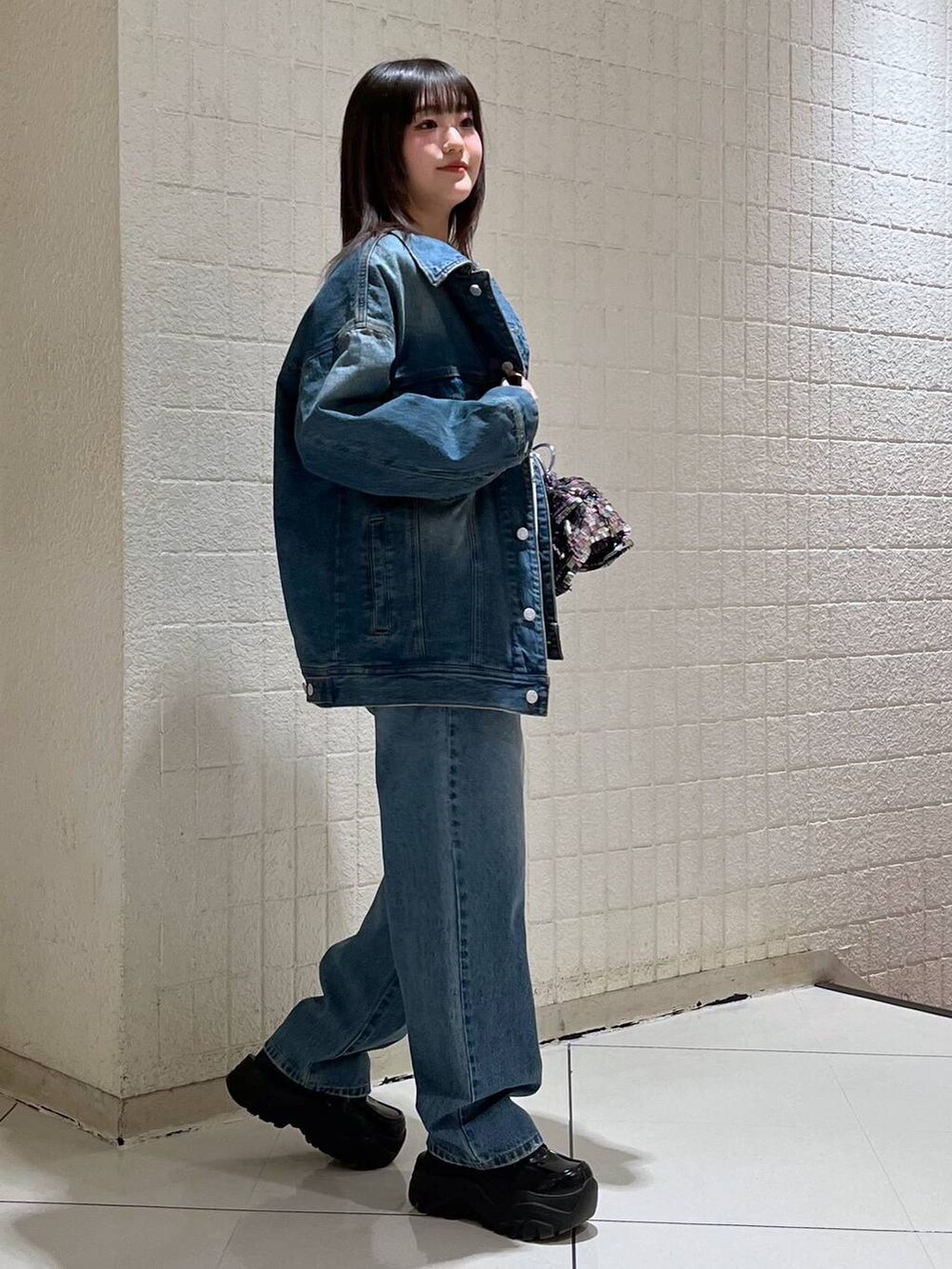 ホワイト系のニット/セーター、ブルー系のデニムジャケット、ブルー系のデニムパンツを着用したレディースの冬コーディネートの3枚目の写真