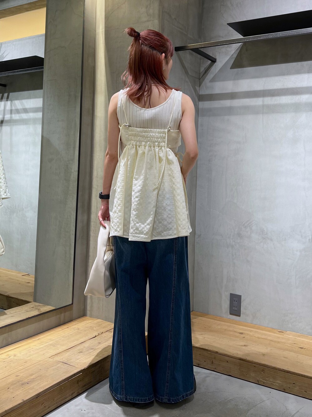 ホワイト系のハンドバッグ、ホワイト系のキャミソール、ブルー系のデニムパンツを着用したレディースの夏コーディネートの3枚目の写真