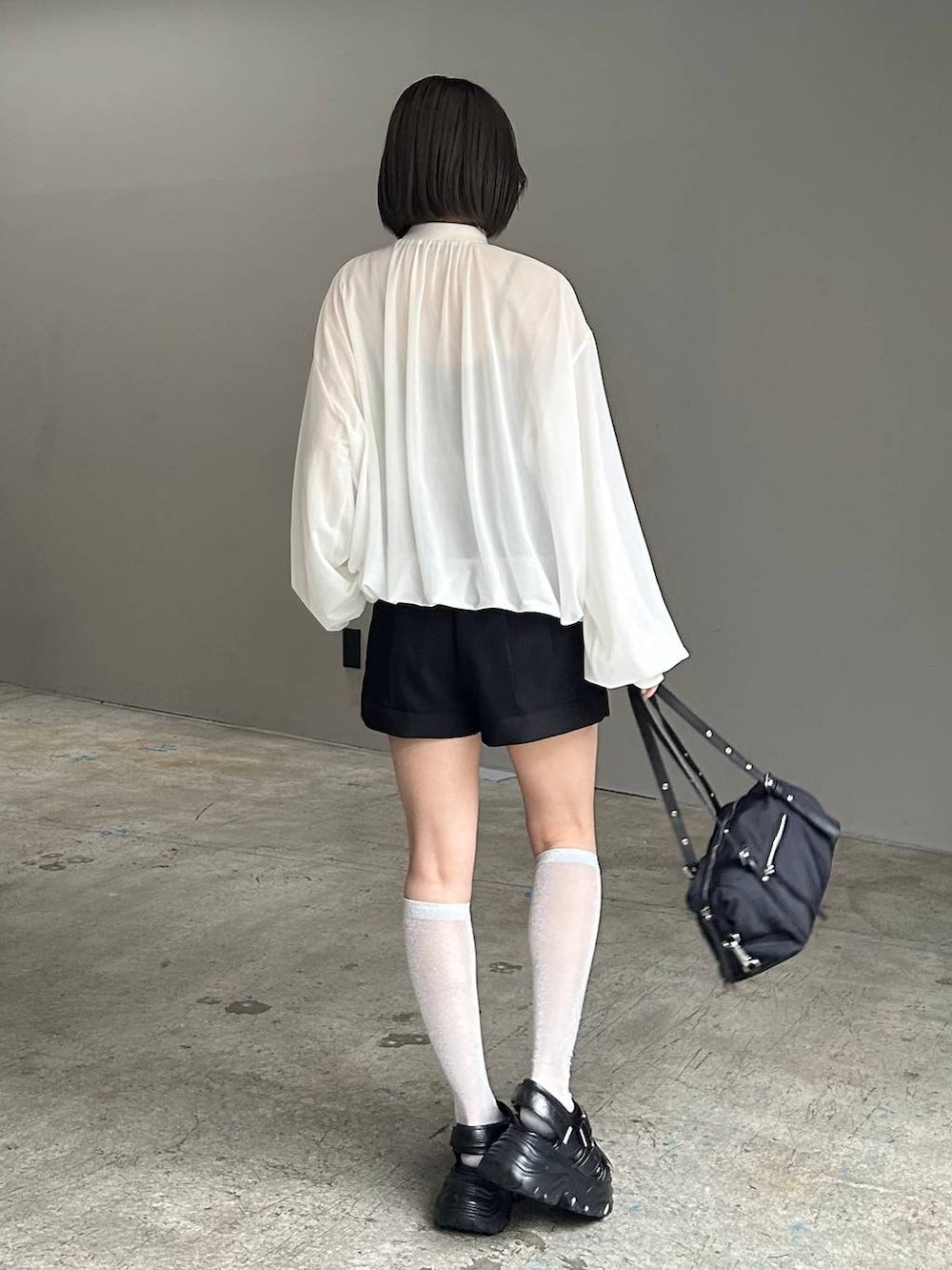 ブラック系のキャミソール、ホワイト系のブルゾン、ブラック系のサンダルを着用したレディースの春コーディネートの3枚目の写真