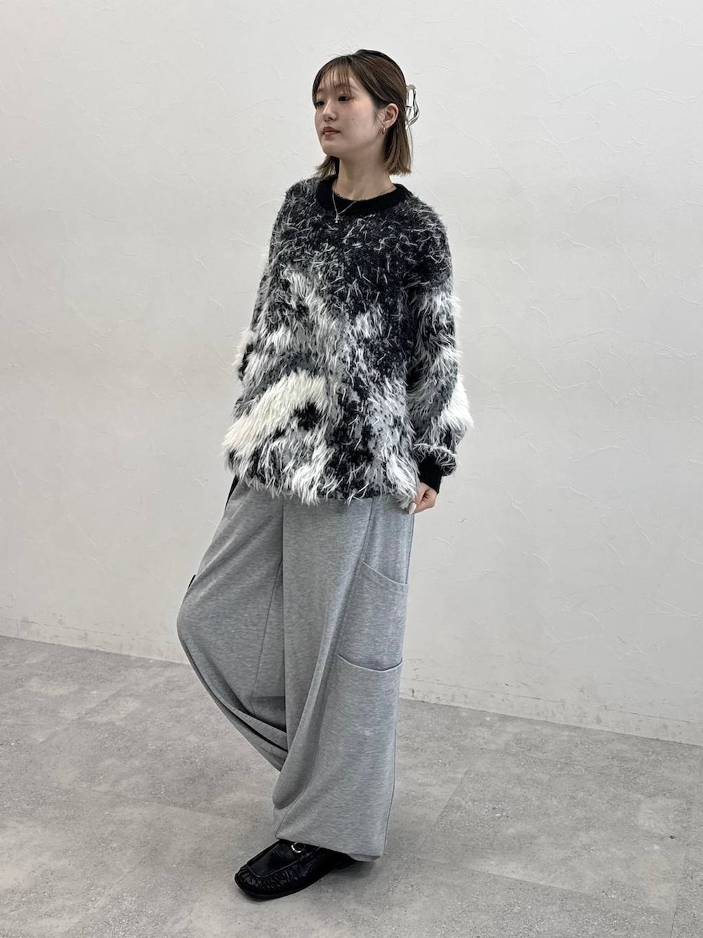 ブラック系のニット/セーター、グレー系のスウェットパンツ、ブラック系のローファーを着用したレディースの夏コーディネートの4枚目の写真