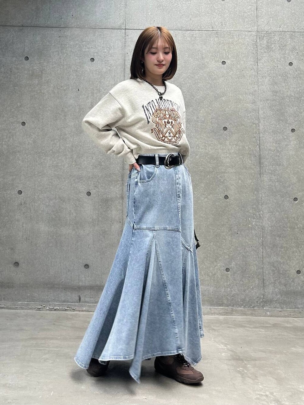 ブラウン系のスニーカー、グレー系のスウェット、ブルー系のデニムスカートを着用したレディースの冬コーディネートの2枚目の写真