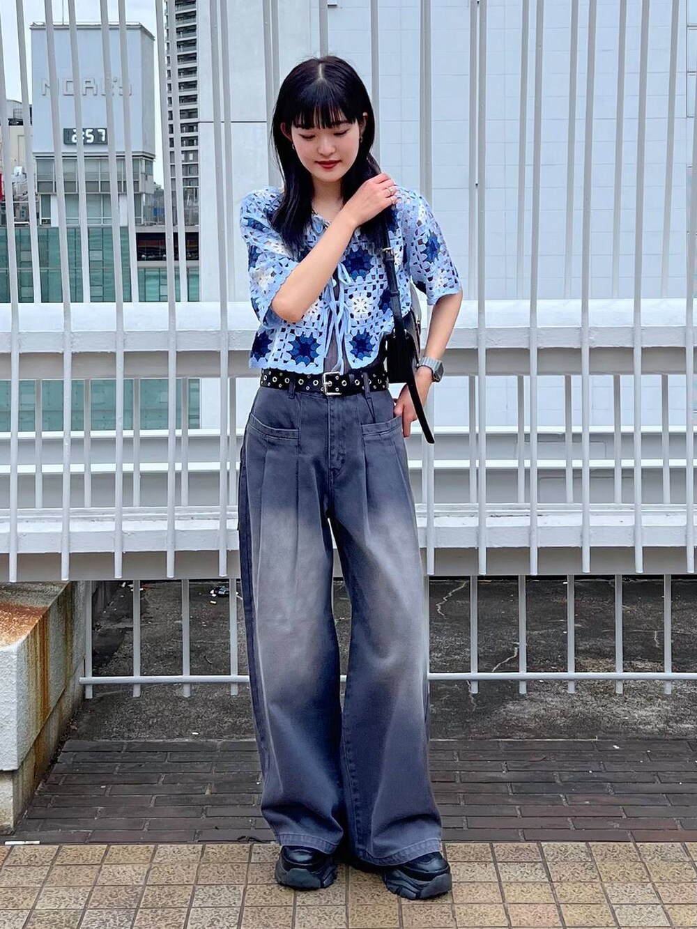 グレー系のタンクトップ、ブラック系のスニーカー、ブラック系のハンドバッグを着用したレディースの夏コーディネートの2枚目の写真