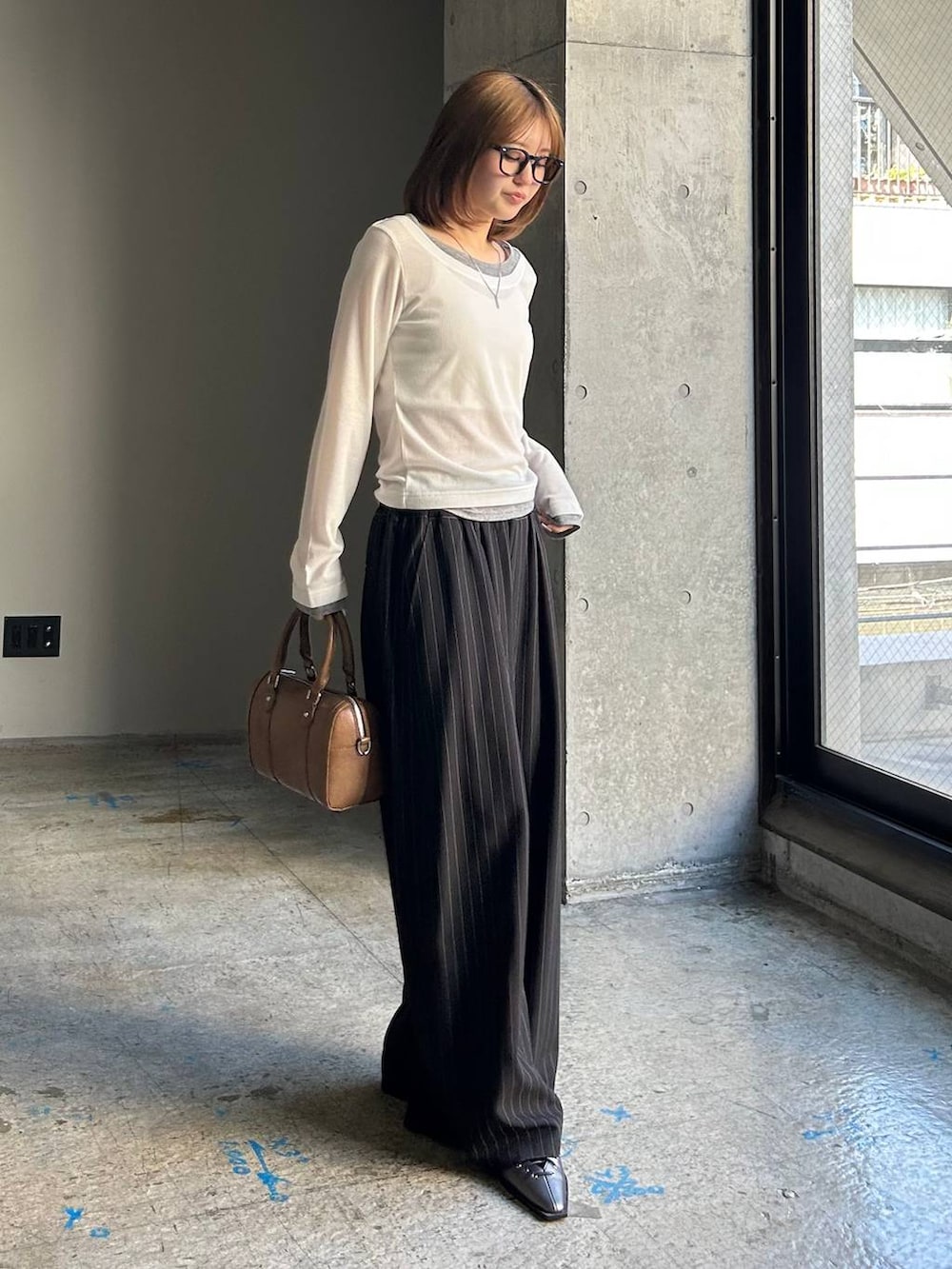 ブラウン系のボストンバッグ、ブラック系のサンダル、ブラック系のスラックスを着用したレディースの冬コーディネートの2枚目の写真