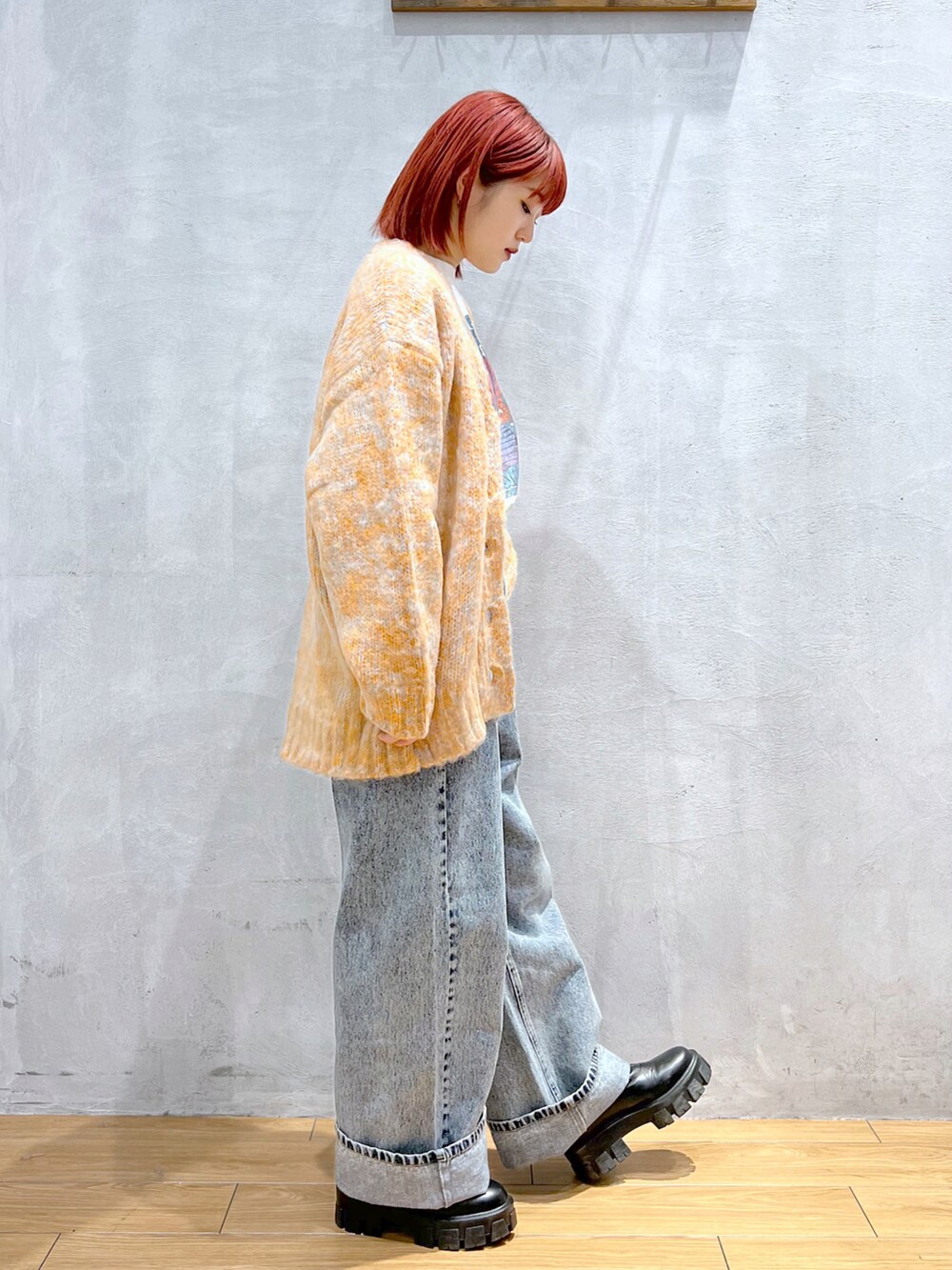 オレンジ系のカーディガン/ボレロ、ホワイト系のTシャツ/カットソー、ブルー系のデニムパンツを着用したレディースの秋コーディネートの2枚目の写真