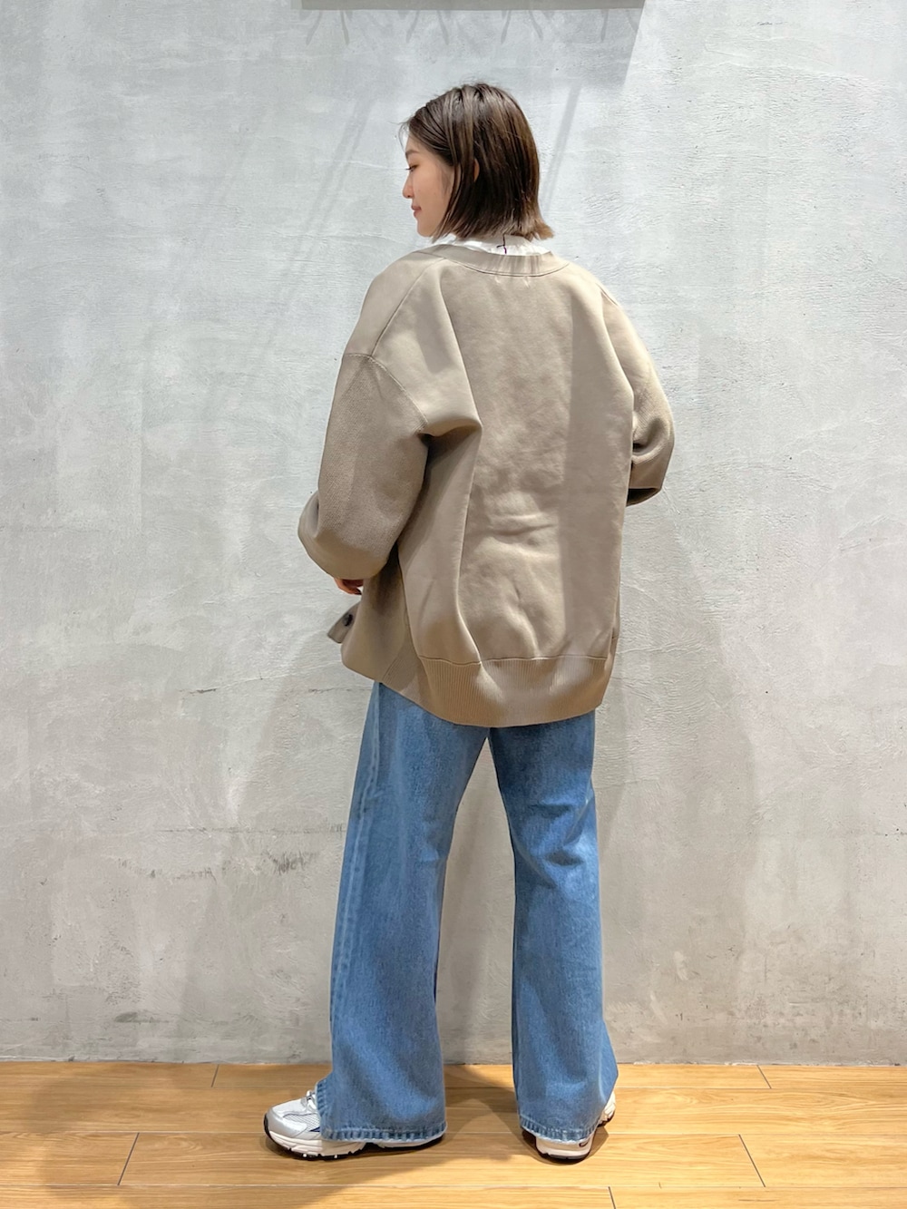 ブルー系のデニムパンツ、グレー系のスニーカー、ホワイト系のTシャツ/カットソーを着用したレディースの秋コーディネートの3枚目の写真