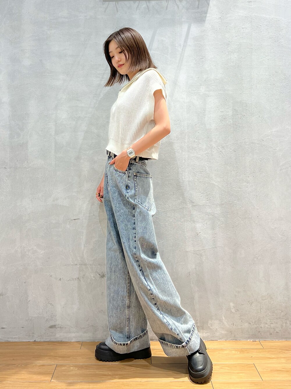 ホワイト系のニット/セーター、ブルー系のデニムパンツ、ブラック系のブーツを着用したレディースの夏コーディネートの2枚目の写真