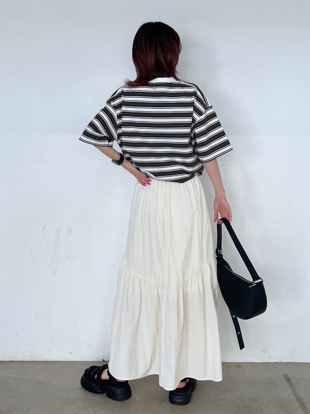 ブラック系のショルダーバッグ、ホワイト系のTシャツ/カットソー、ブラック系のサンダルを着用したレディースの春コーディネートの2枚目の写真