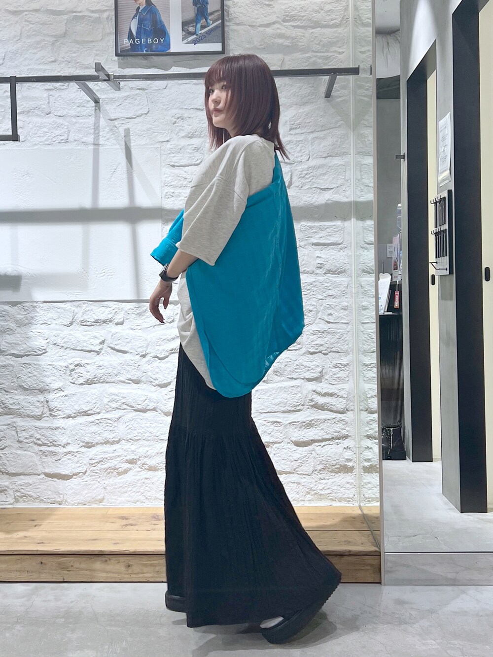 ブラック系のスカート、ベージュ系のTシャツ/カットソーを着用したレディースの春コーディネートの2枚目の写真