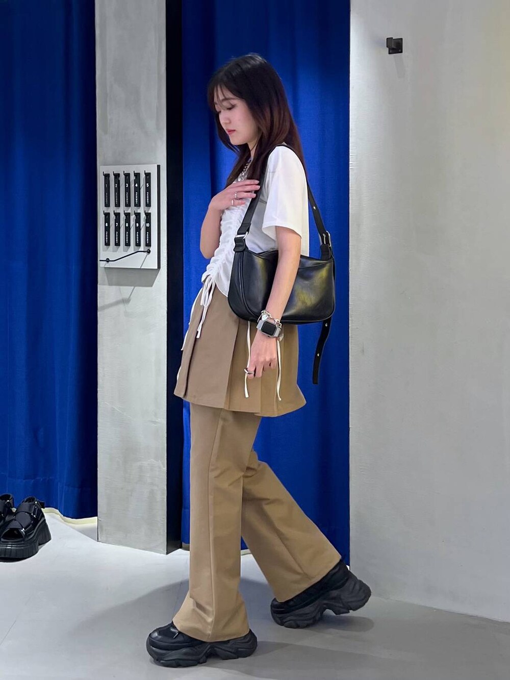 ブラック系のスニーカー、ブラック系のショルダーバッグ、ホワイト系のTシャツ/カットソーを着用したレディースの春コーディネートの3枚目の写真