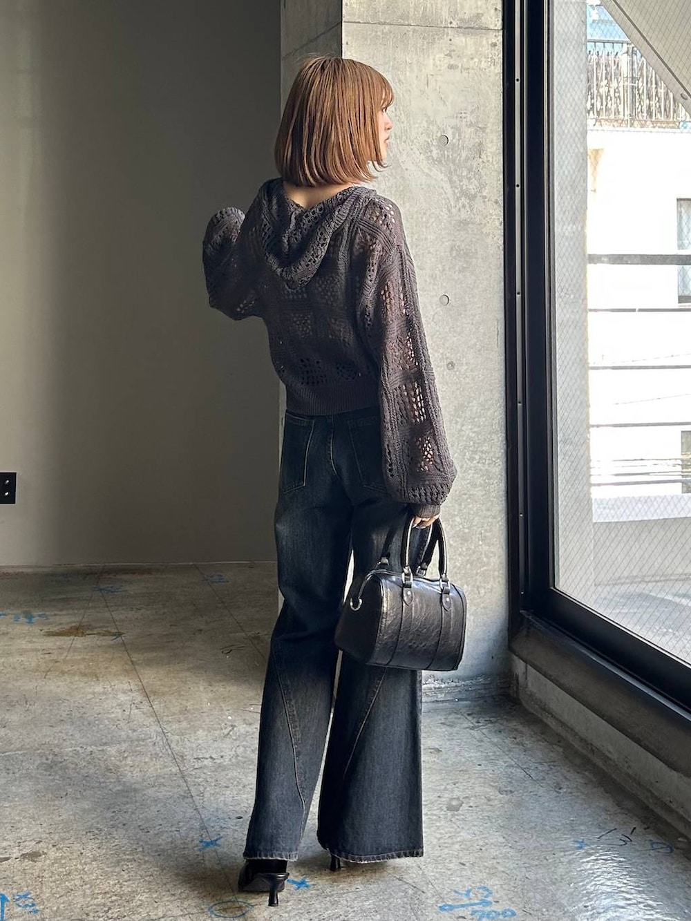 ブルー系のデニムパンツ、ブラック系のボストンバッグ、ブラック系のサンダルを着用したレディースの冬コーディネートの5枚目の写真