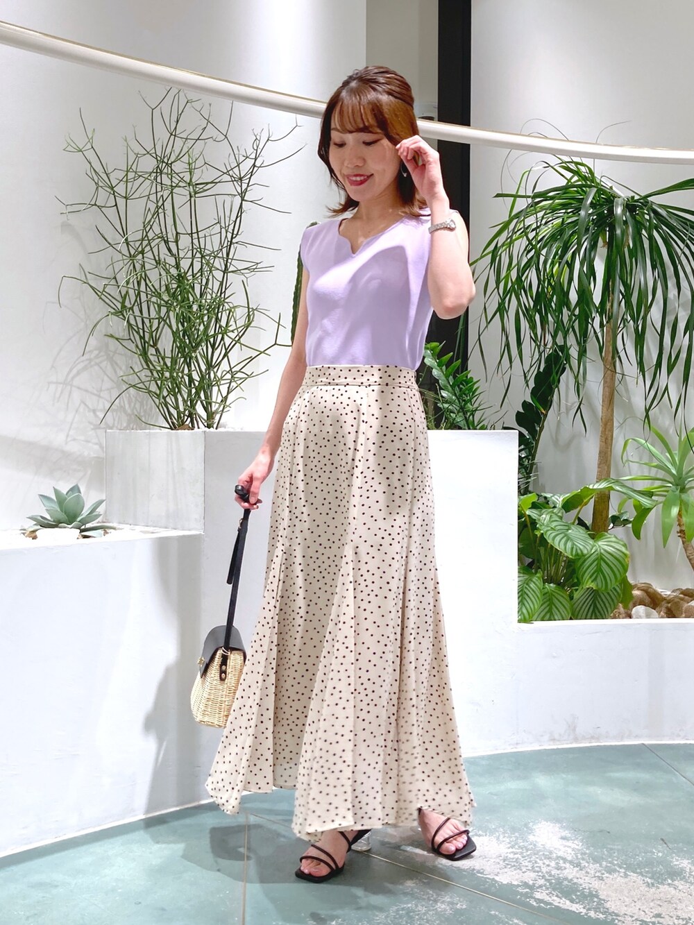 パープル系のニット/セーター、ベージュ系のスカート、ベージュ系のショルダーバッグを着用したレディースの春コーディネートの2枚目の写真