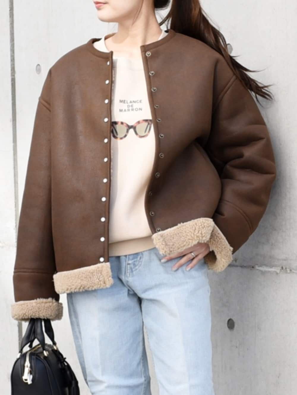 ブルー系のデニムパンツ、ブラック系のボストンバッグ、ブラウン系のノーカラーコートを着用したレディースの秋コーディネートの2枚目の写真