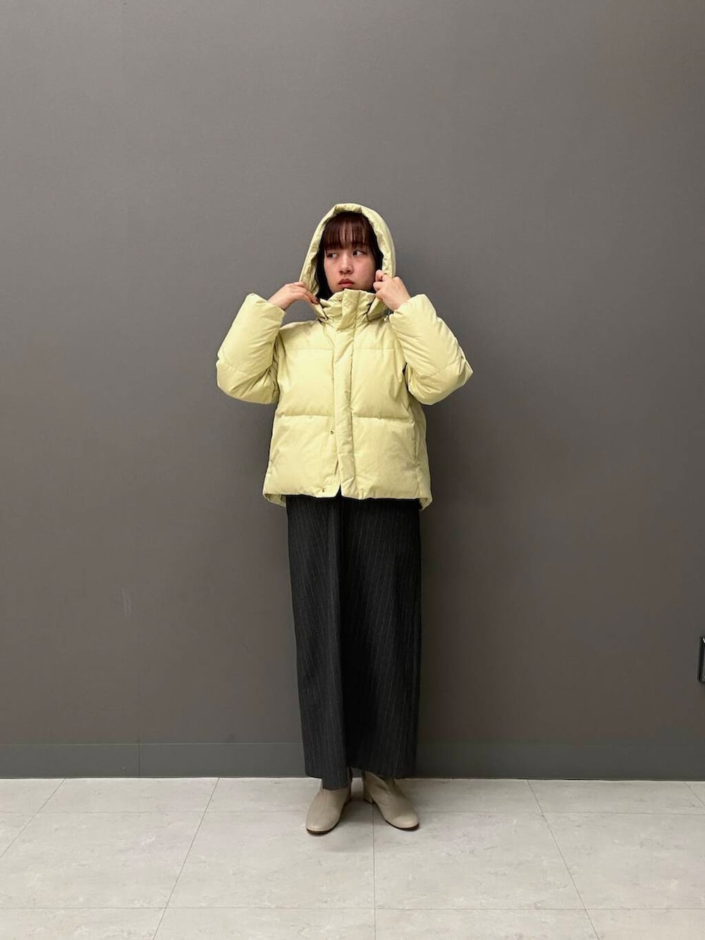 ホワイト系のブーツ、グレー系のワンピース、イエロー系のダウンジャケット/コートを着用したレディースの冬コーディネートの3枚目の写真