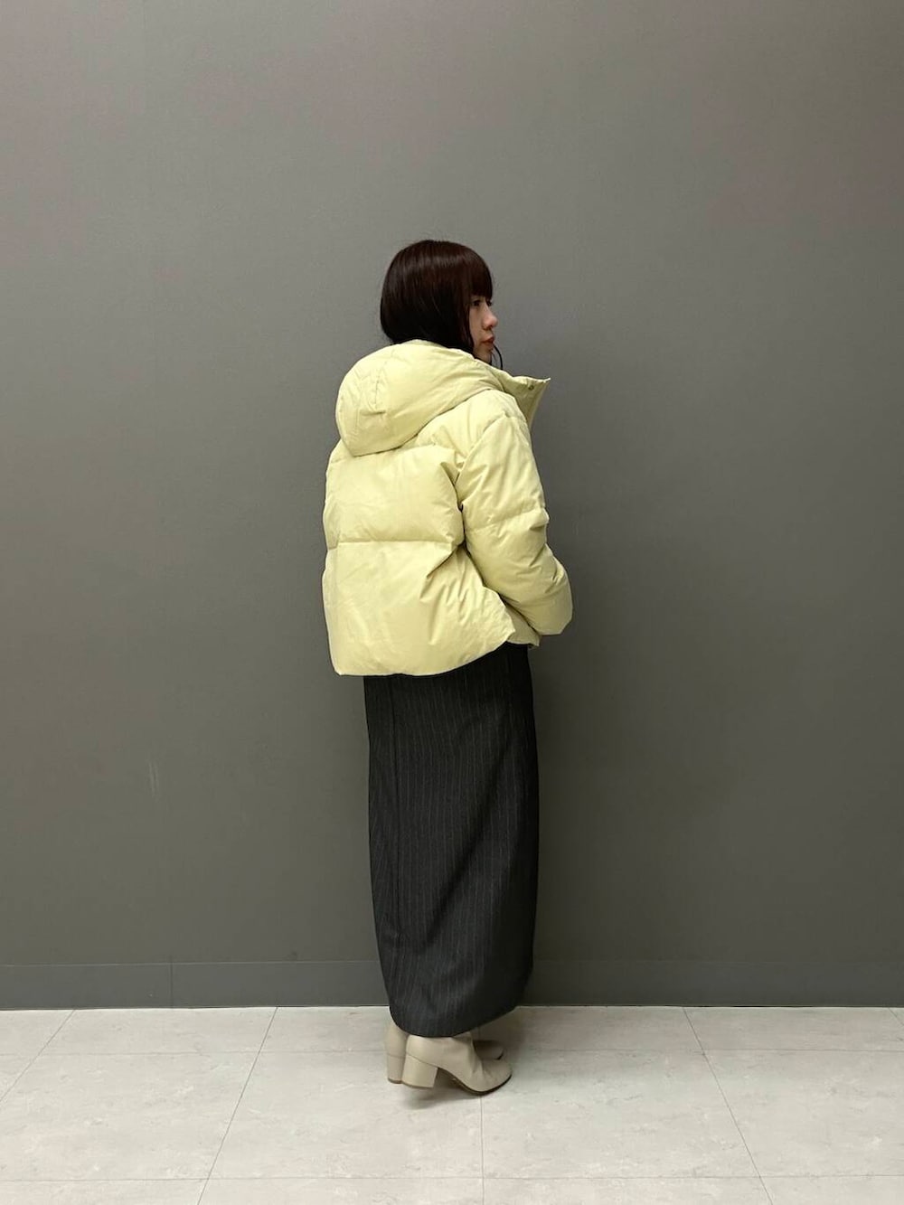 ホワイト系のブーツ、グレー系のワンピース、イエロー系のダウンジャケット/コートを着用したレディースの冬コーディネートの2枚目の写真