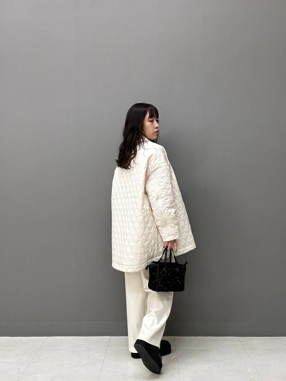 ホワイト系のダウンジャケット/コート、ホワイト系のその他パンツ、ブラック系のハンドバッグを着用したレディースの秋コーディネートの4枚目の写真