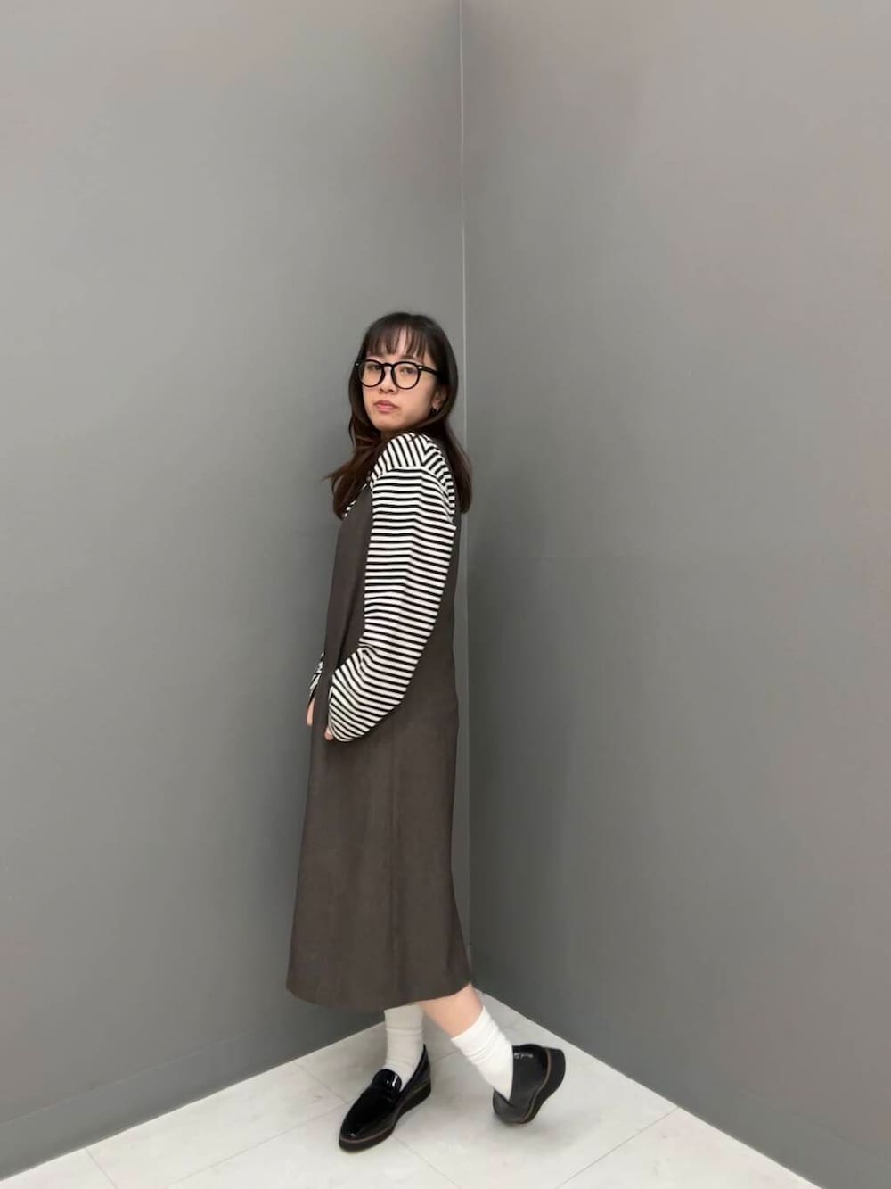 ブラック系のローファー、ホワイト系のTシャツ/カットソー、ブラウン系のワンピースを着用したレディースの秋コーディネートの2枚目の写真