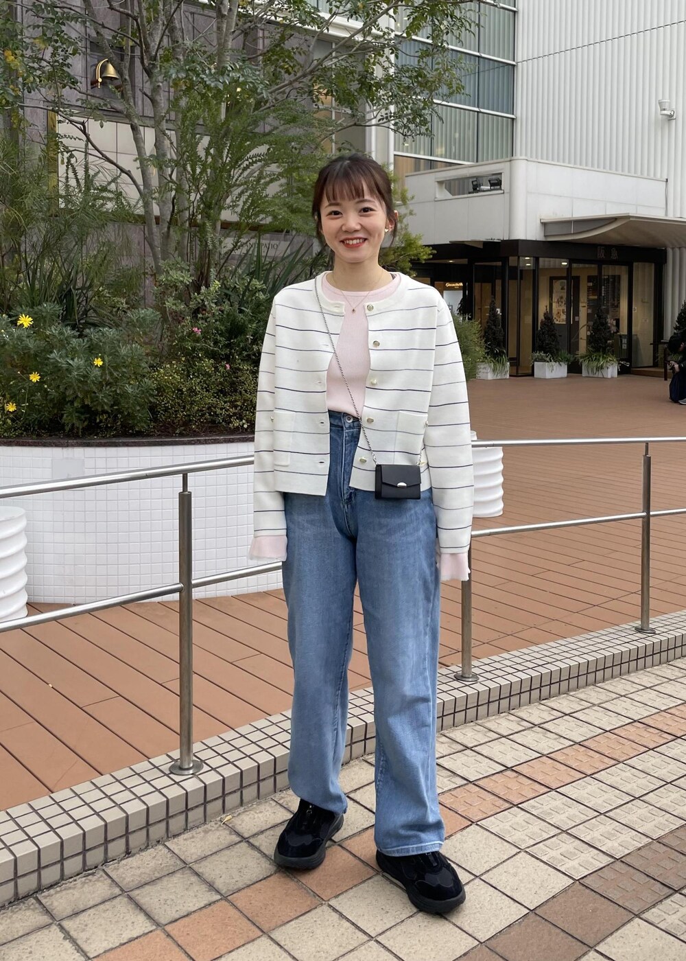 ブラック系のショルダーバッグ、ピンク系のニット/セーター、ホワイト系のカーディガン/ボレロを着用したレディースの冬コーディネートの2枚目の写真