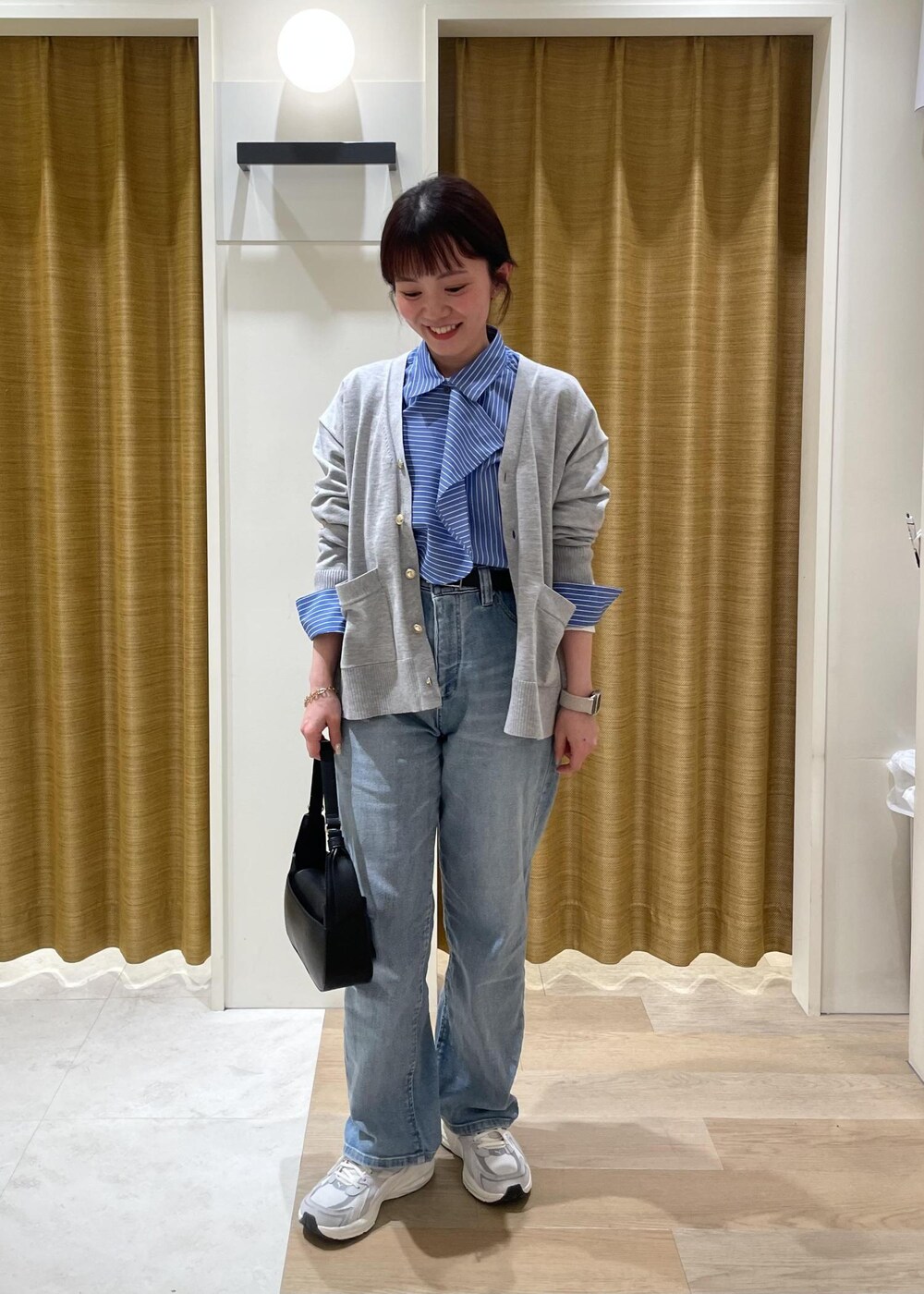 ブルー系のシャツ/ブラウス、グレー系のカーディガン/ボレロ、ブラック系のハンドバッグを着用したレディースの春コーディネートの2枚目の写真