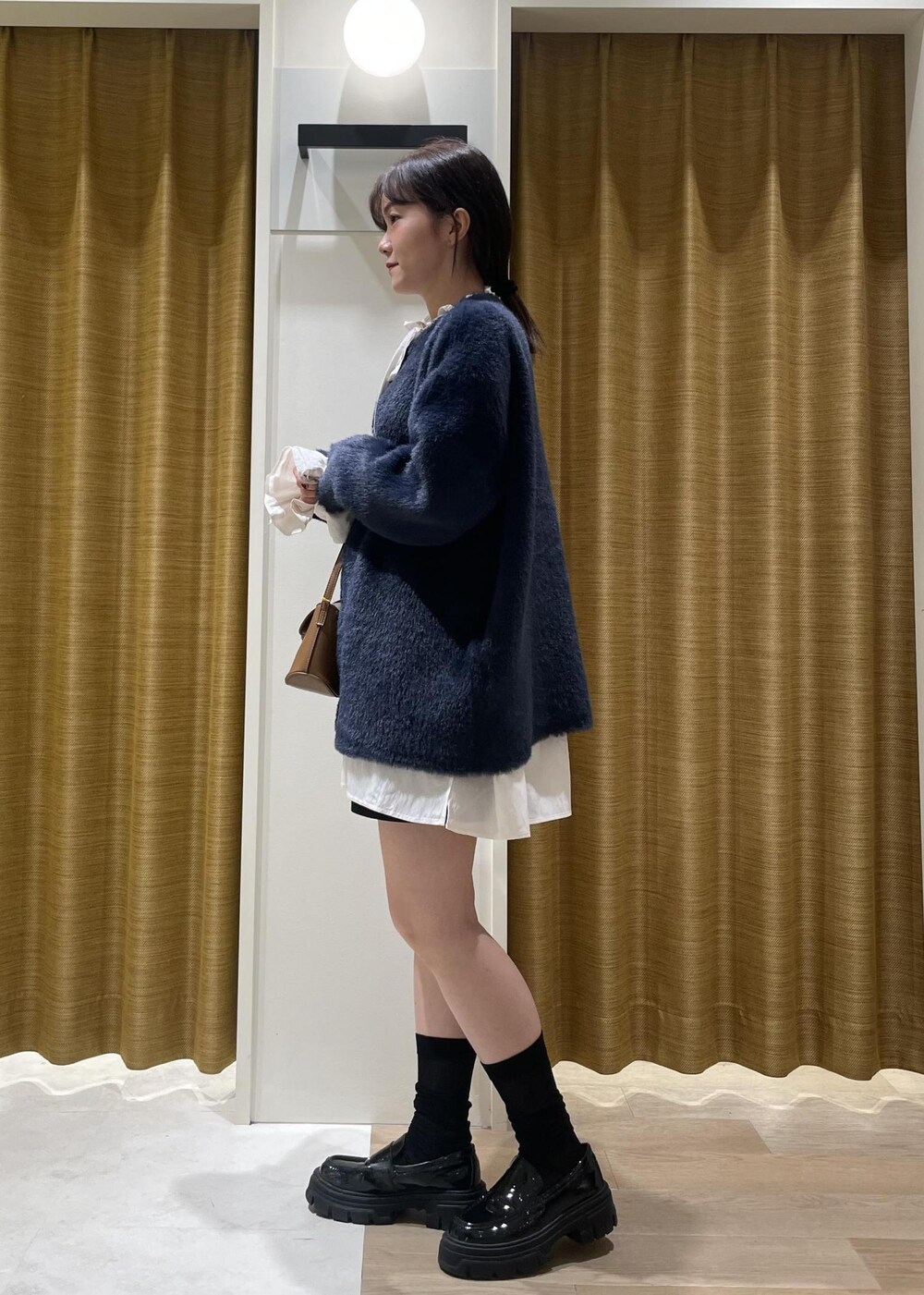 ブラック系のチノパンツ、ブラウン系のショルダーバッグ、ホワイト系のシャツ/ブラウスを着用したレディースの秋コーディネートの5枚目の写真
