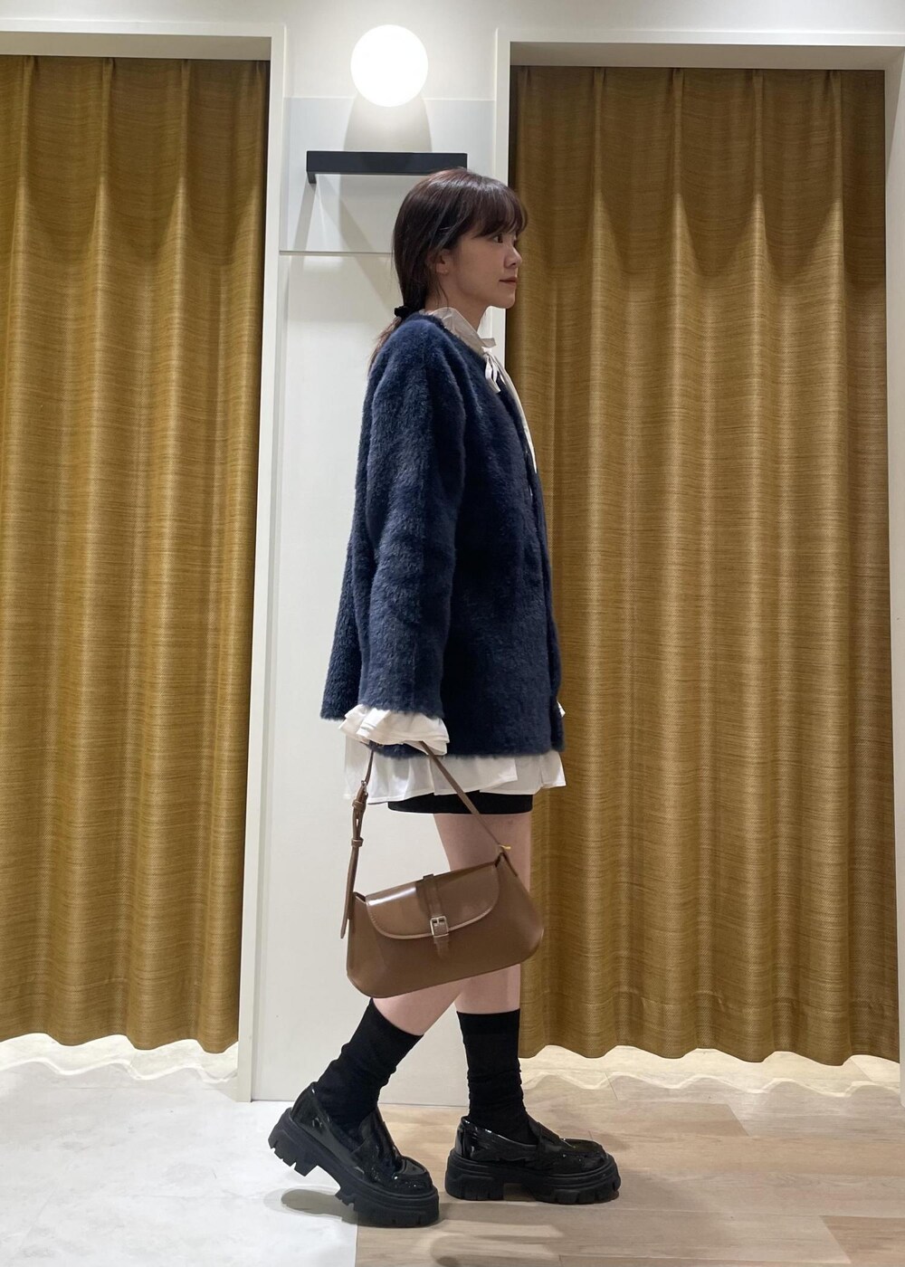 ブラック系のチノパンツ、ブラウン系のショルダーバッグ、ホワイト系のシャツ/ブラウスを着用したレディースの秋コーディネートの3枚目の写真