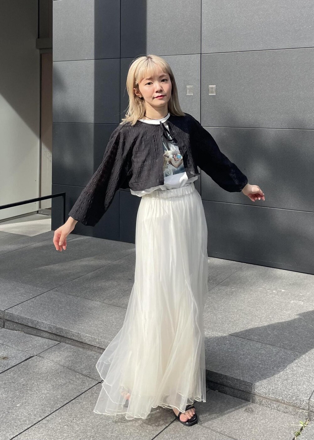 ブラック系のサンダル、ホワイト系のスカート、ブラック系のカーディガン/ボレロを着用したレディースの夏コーディネートの4枚目の写真