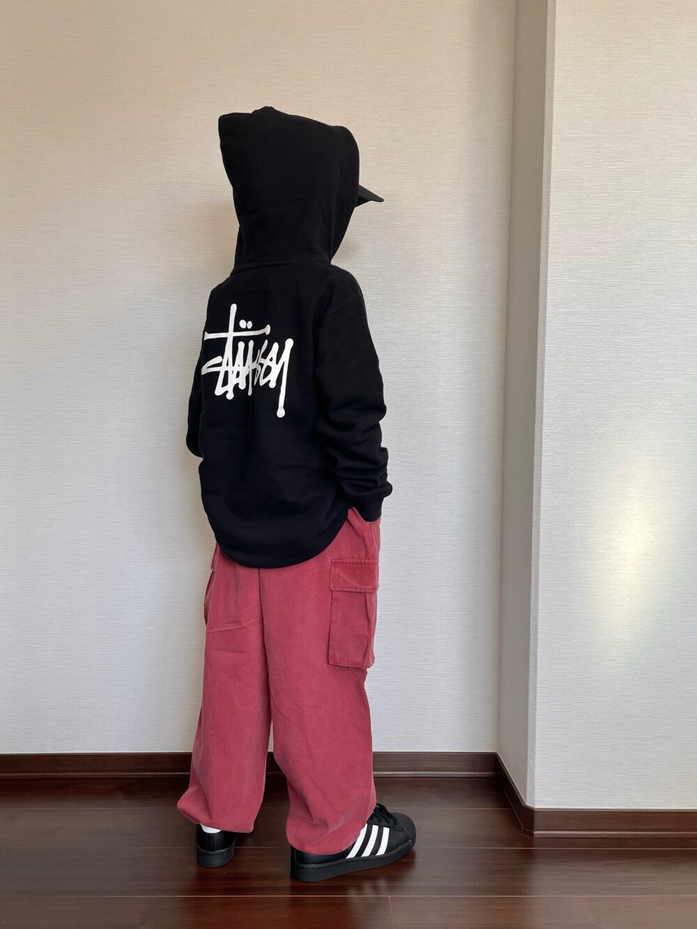 ブラック系のパーカー、オレンジ系のカーゴパンツ、ブラック系のスニーカーを着用したキッズの秋コーディネートの2枚目の写真