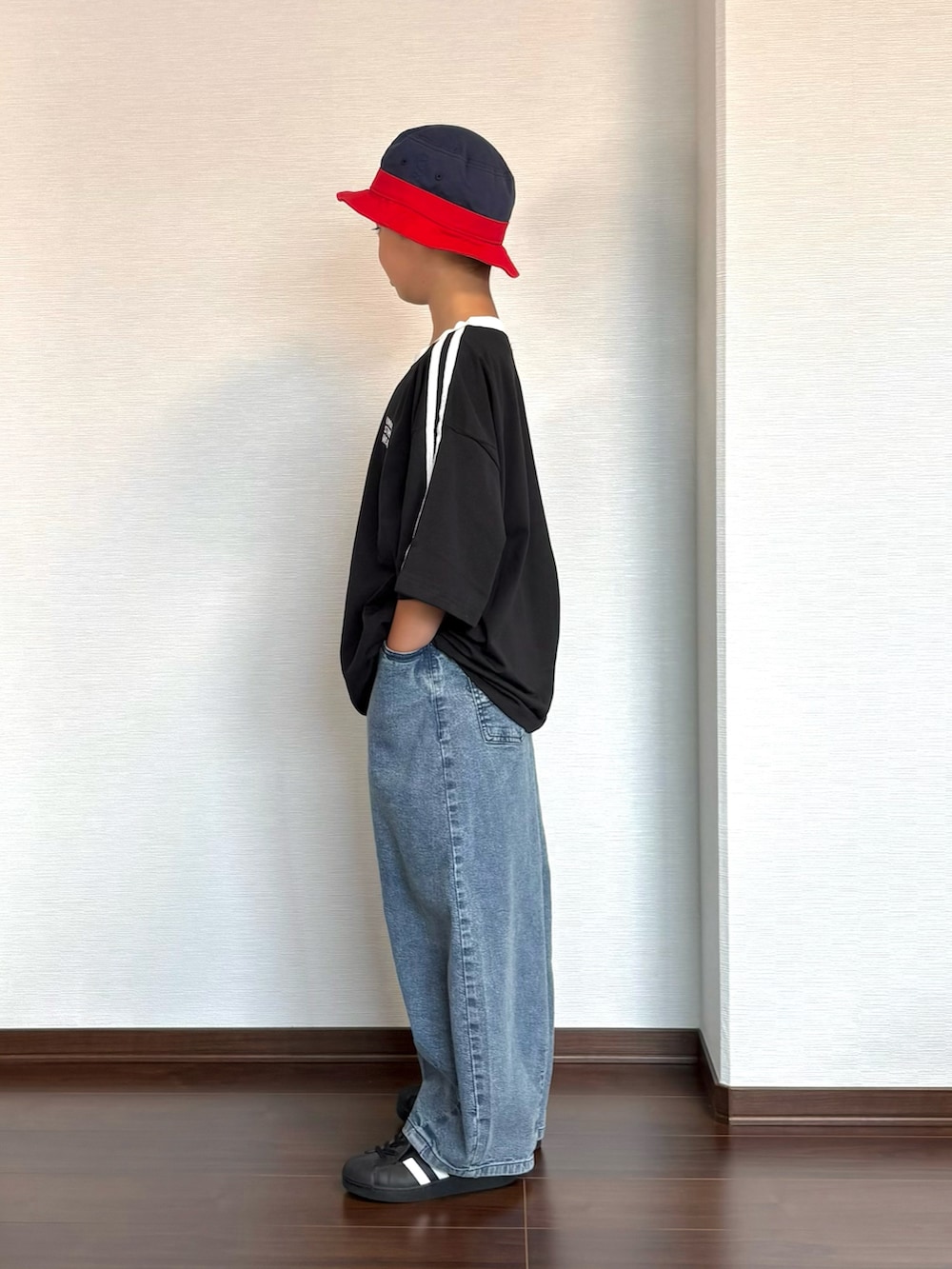 ブラック系のスニーカー、ブラック系のTシャツ/カットソー、ブルー系のデニムパンツを着用したキッズの夏コーディネートの2枚目の写真