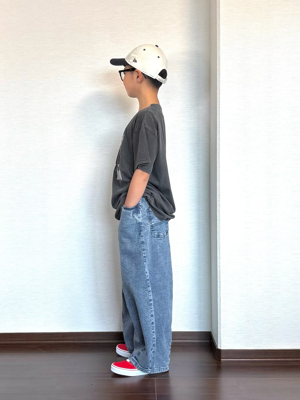 ブラック系のTシャツ/カットソー、ブルー系のデニムパンツ、レッド系のスニーカーを着用したキッズの春コーディネートの2枚目の写真